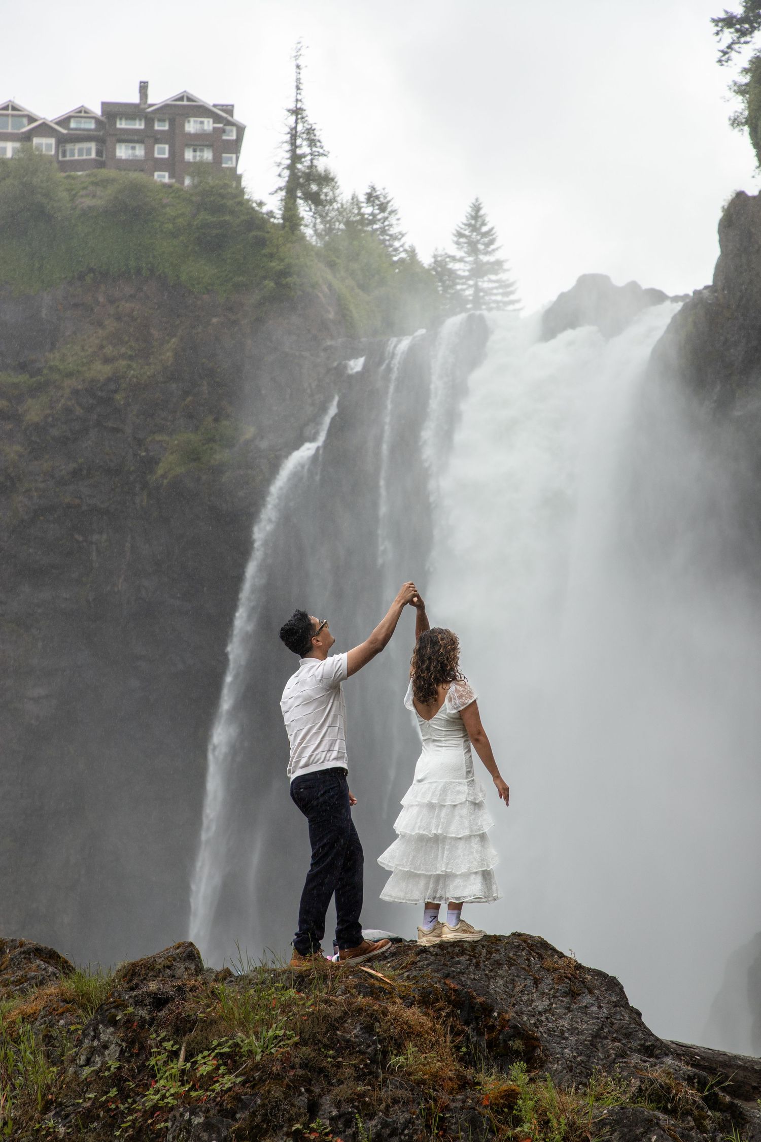 Couple dancing on a rock in front of Snoqualmie Falls during their engagement photoshoot