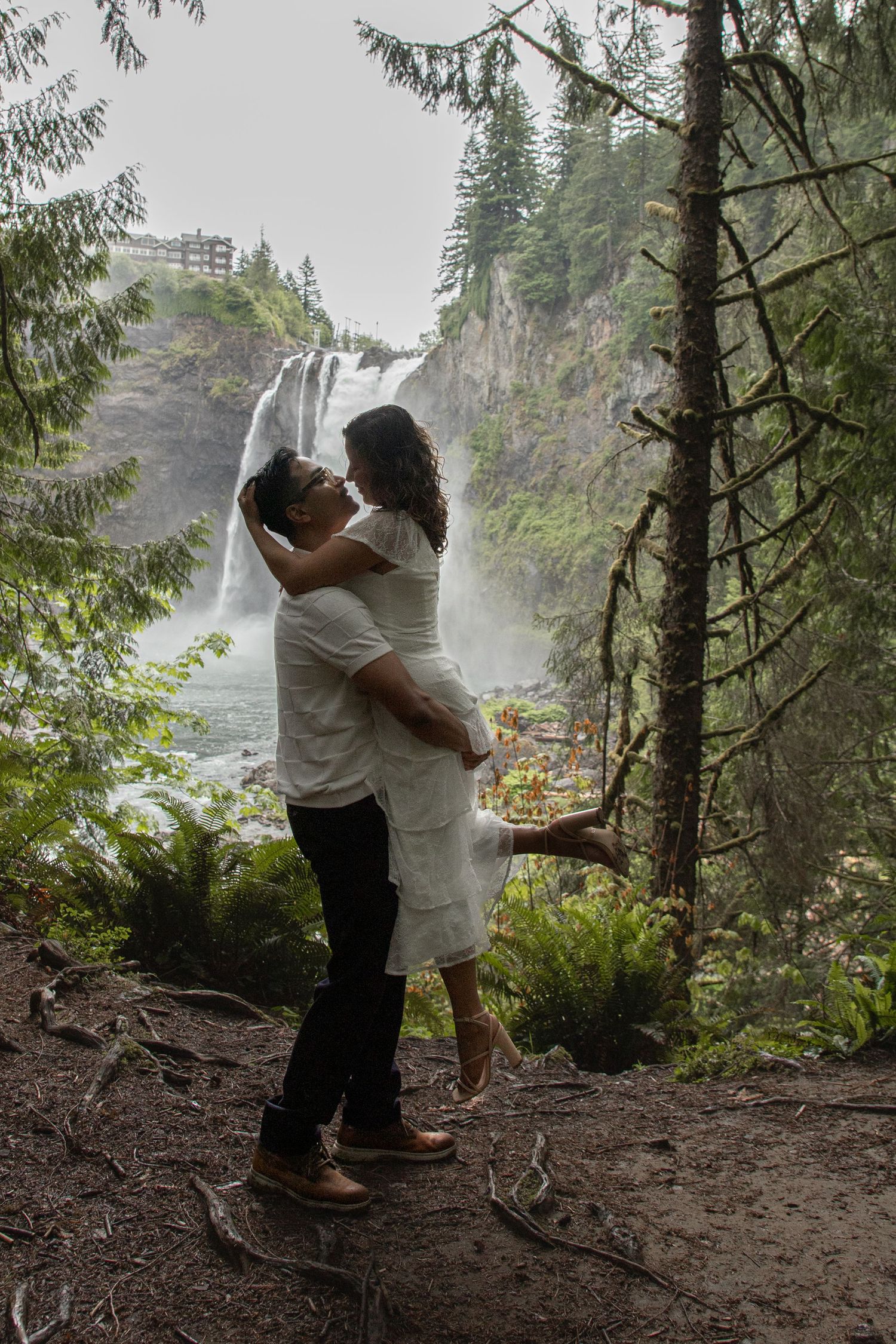 Couple embracing with Snoqualmie Falls in the background after their surprise proposal