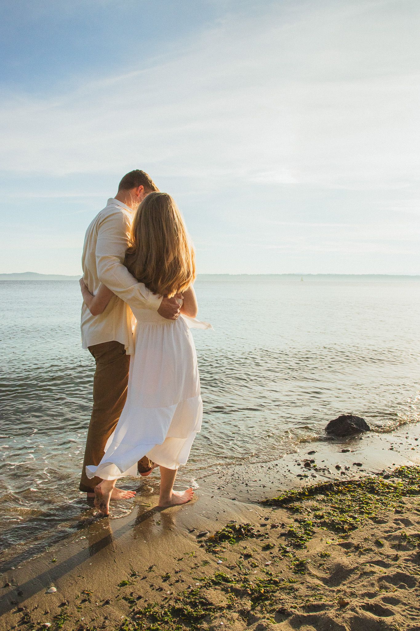 Seattle couples photographer capturing a golden hour couple photoshoot at Discovery Park with Puget Sound views in the background