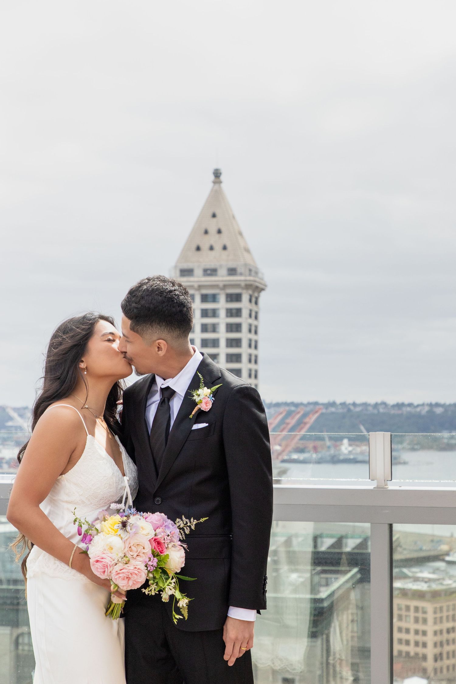 Newlywed couple kissing on the Seattle Municipal Court rooftop with the Smith Tower behind them