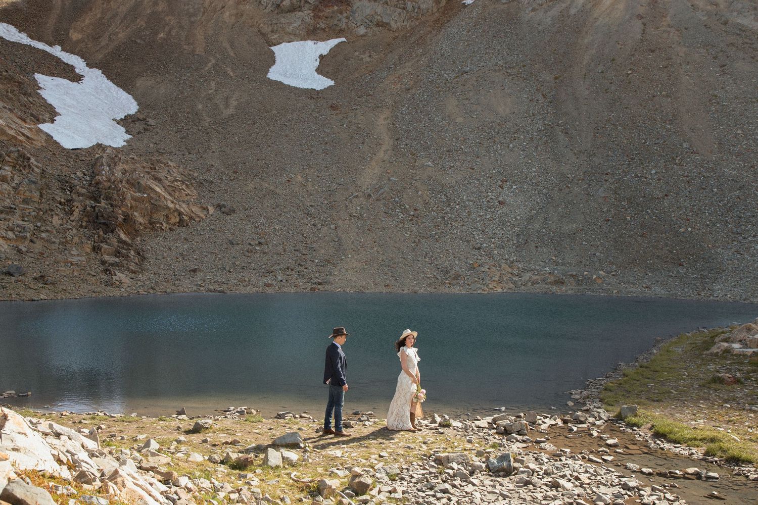 Bride and groom walking along the rocky shore of an alpine lake at Mount Rainier National Park