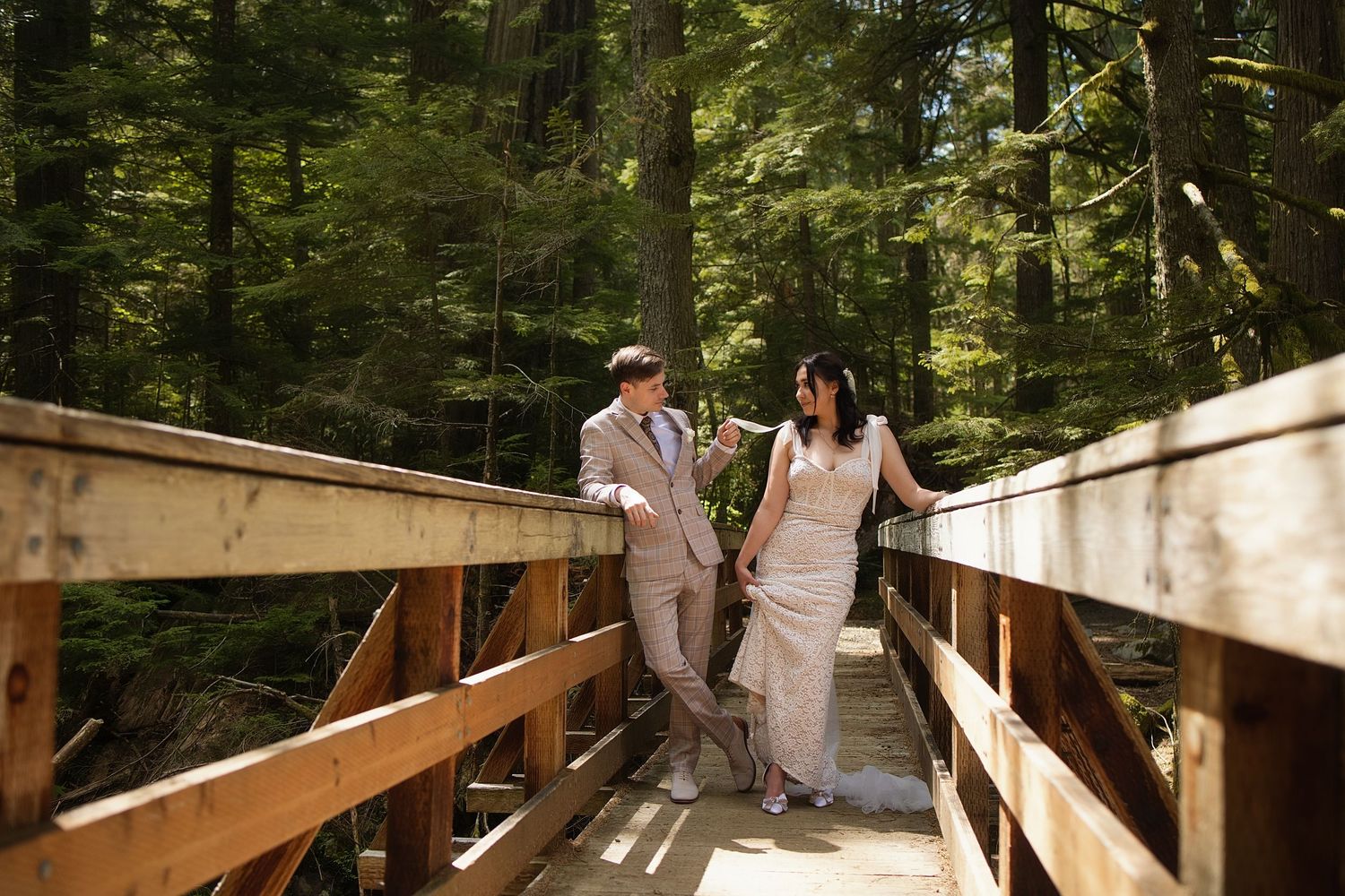 Bride and groom sharing a playful moment on a forest bridge during an intimate Washington elopement photoshoot
