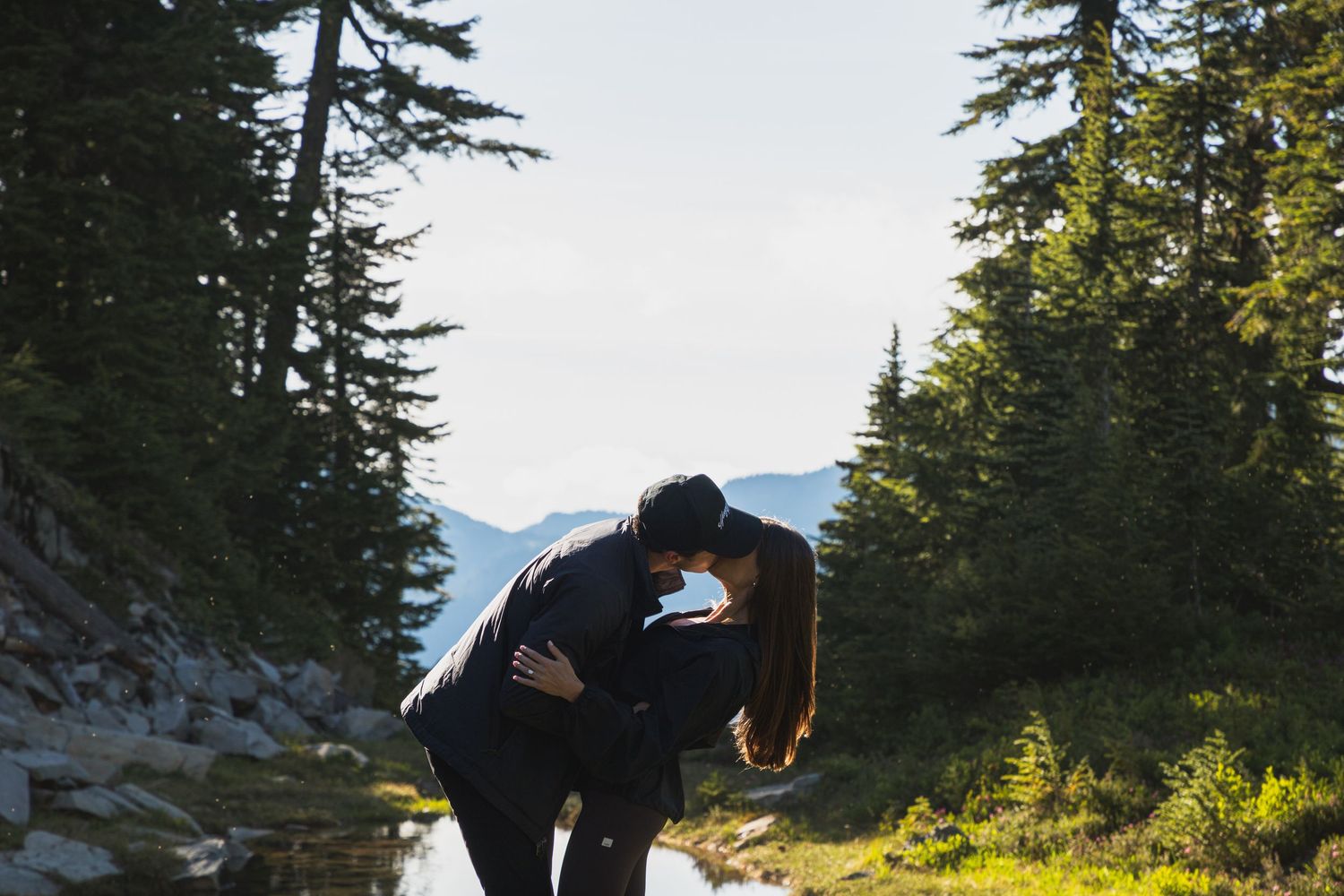 Newly engaged couple kissing beside an alpine pond in Mount Rainier National Park