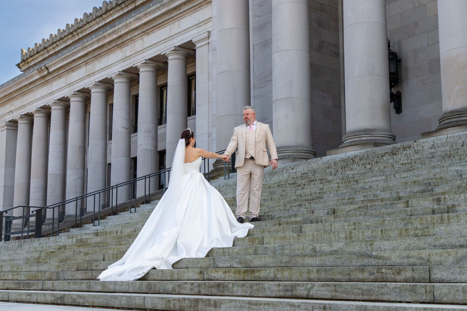 Bride and groom holding hands on the steps of the Washington State Capitol during an elegant Olympia elopement photoshoot