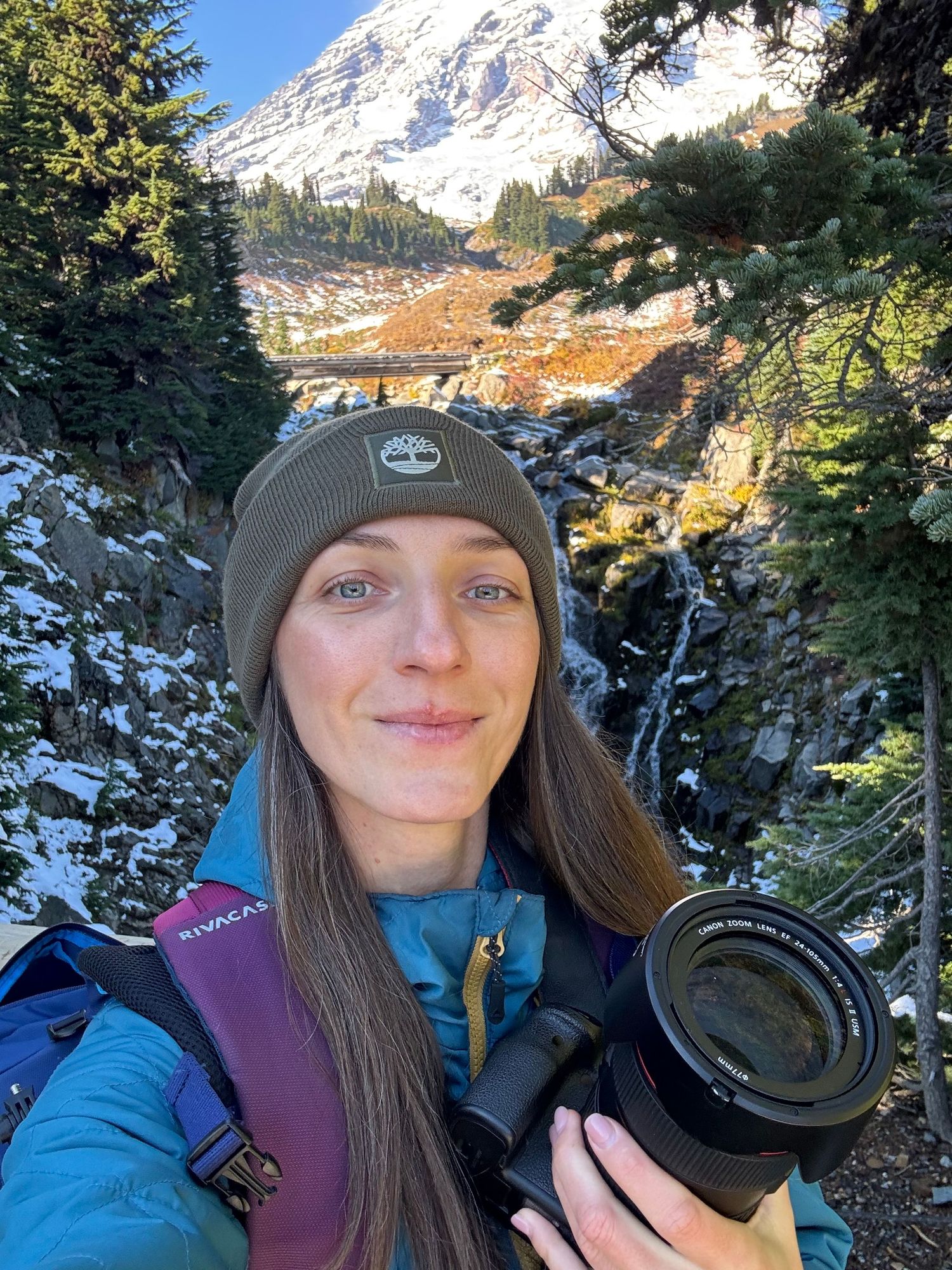 Seattle photographer standing with a camera at Mount Rainier National Park with the mountain in the background