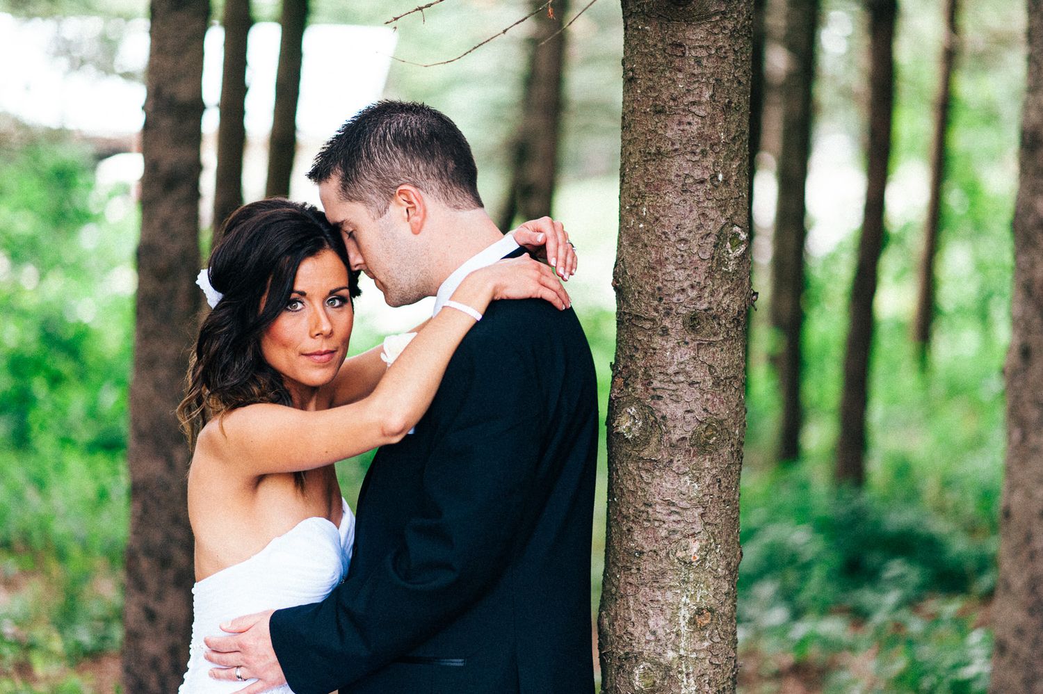 Wedding couple sharing intimate moments in a forest setting.