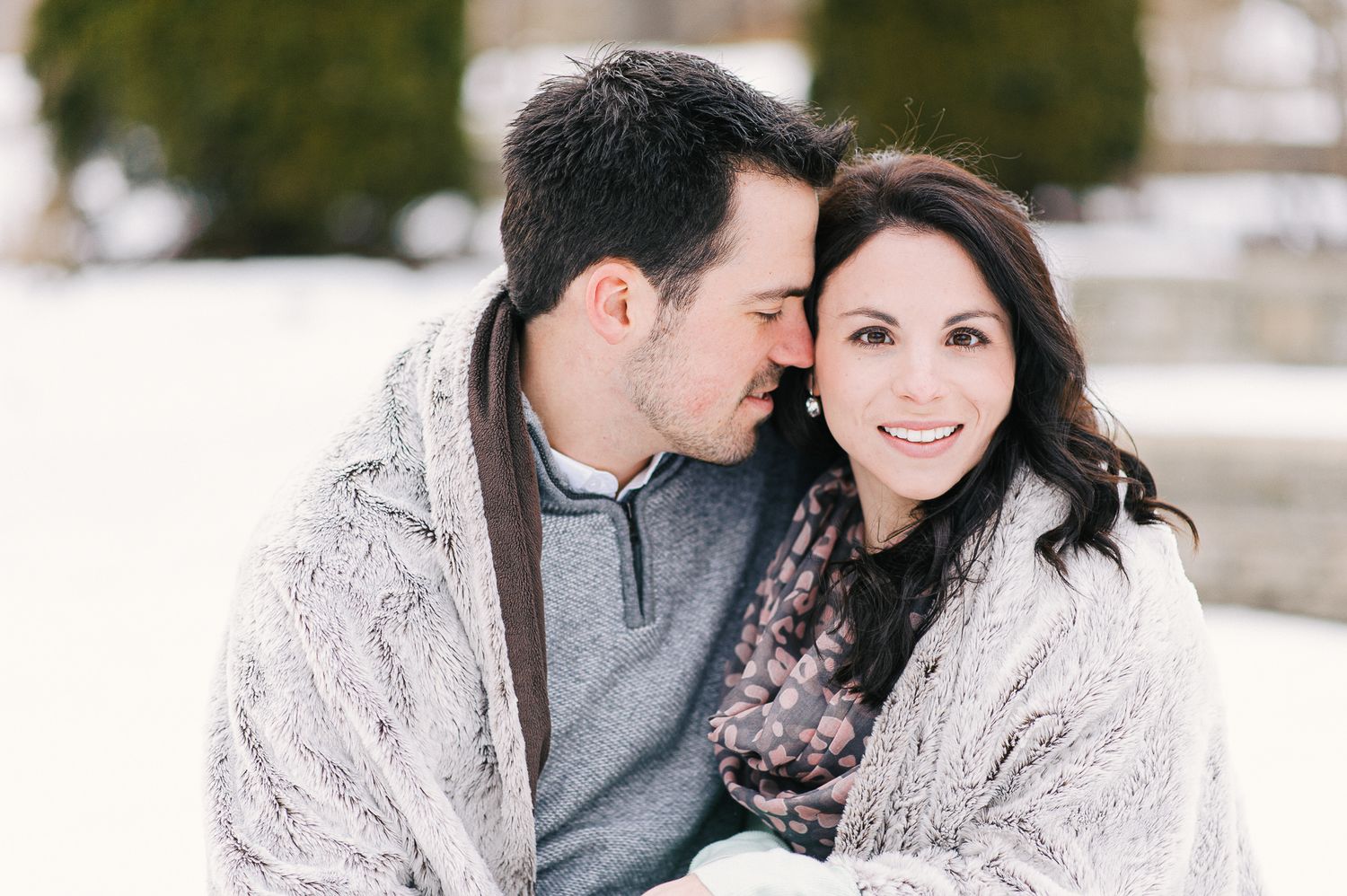 Couple wrapped in cozy blanket during winter photoshoot.