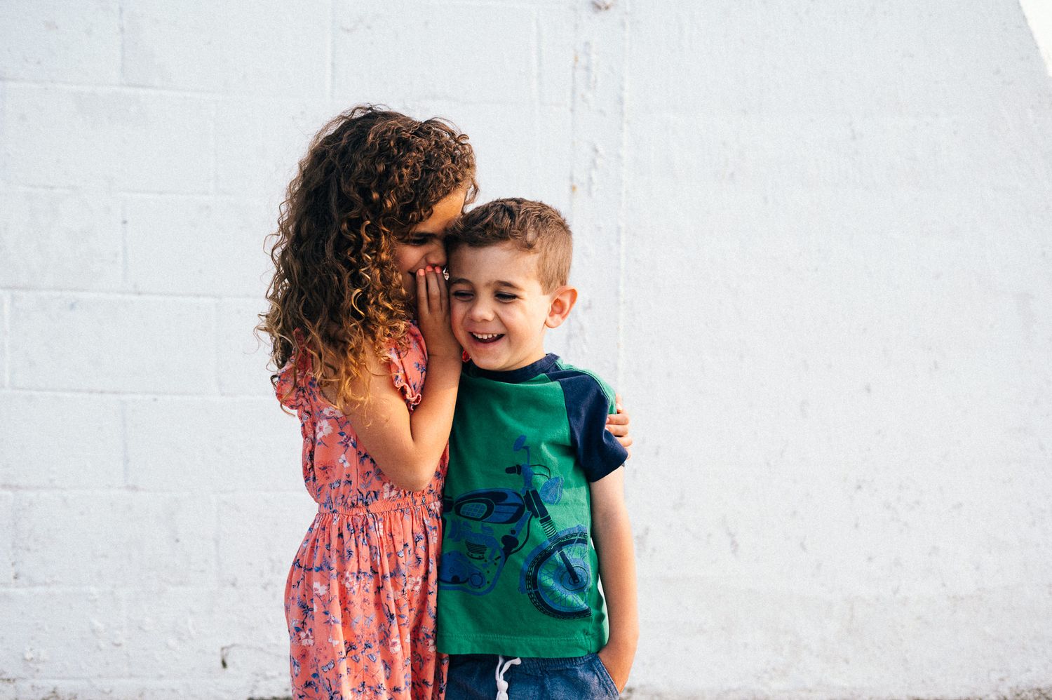Children playing together against white wall background in casual clothing.