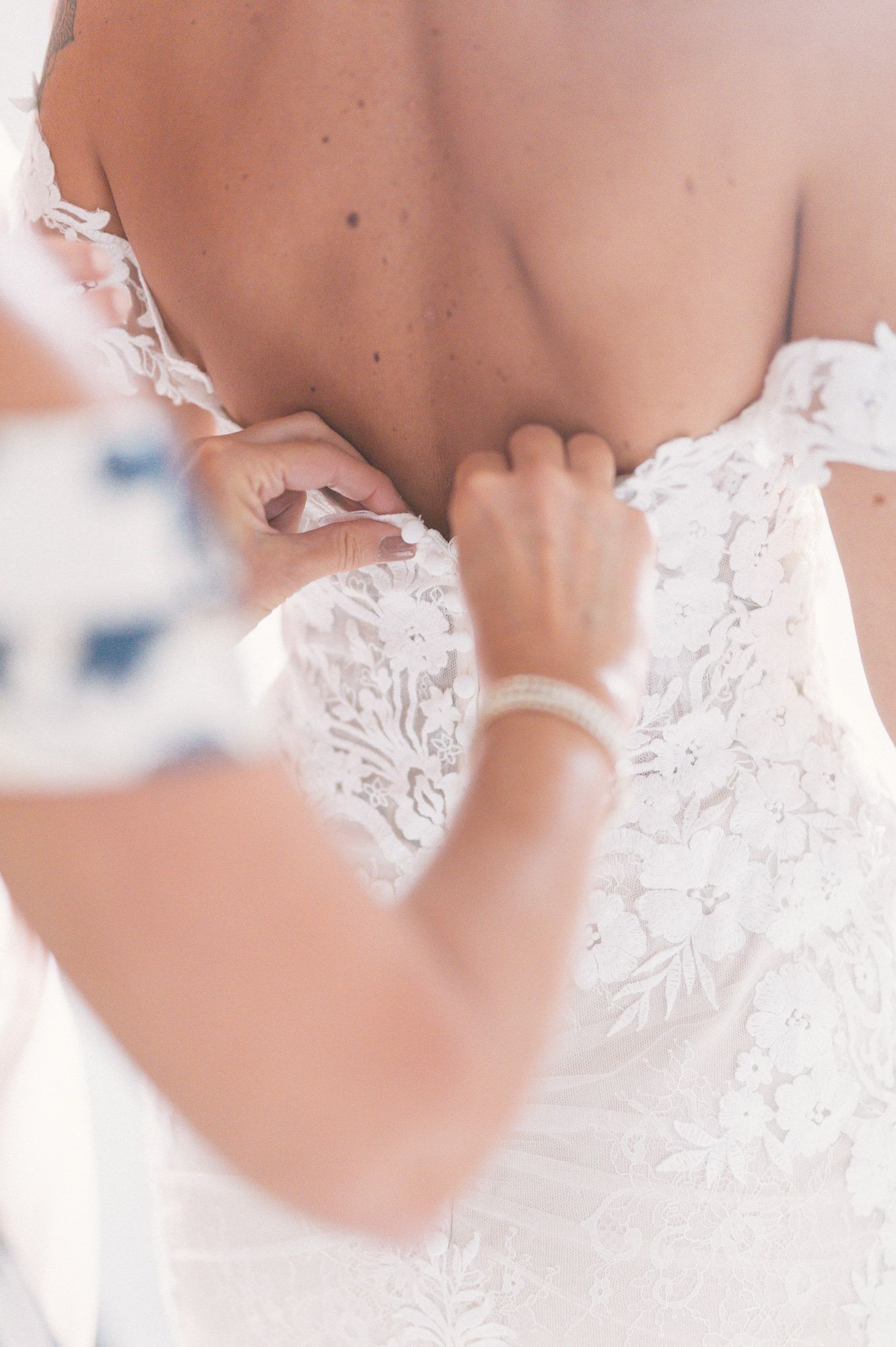 Close-up detail of delicate lace on back of white wedding dress.