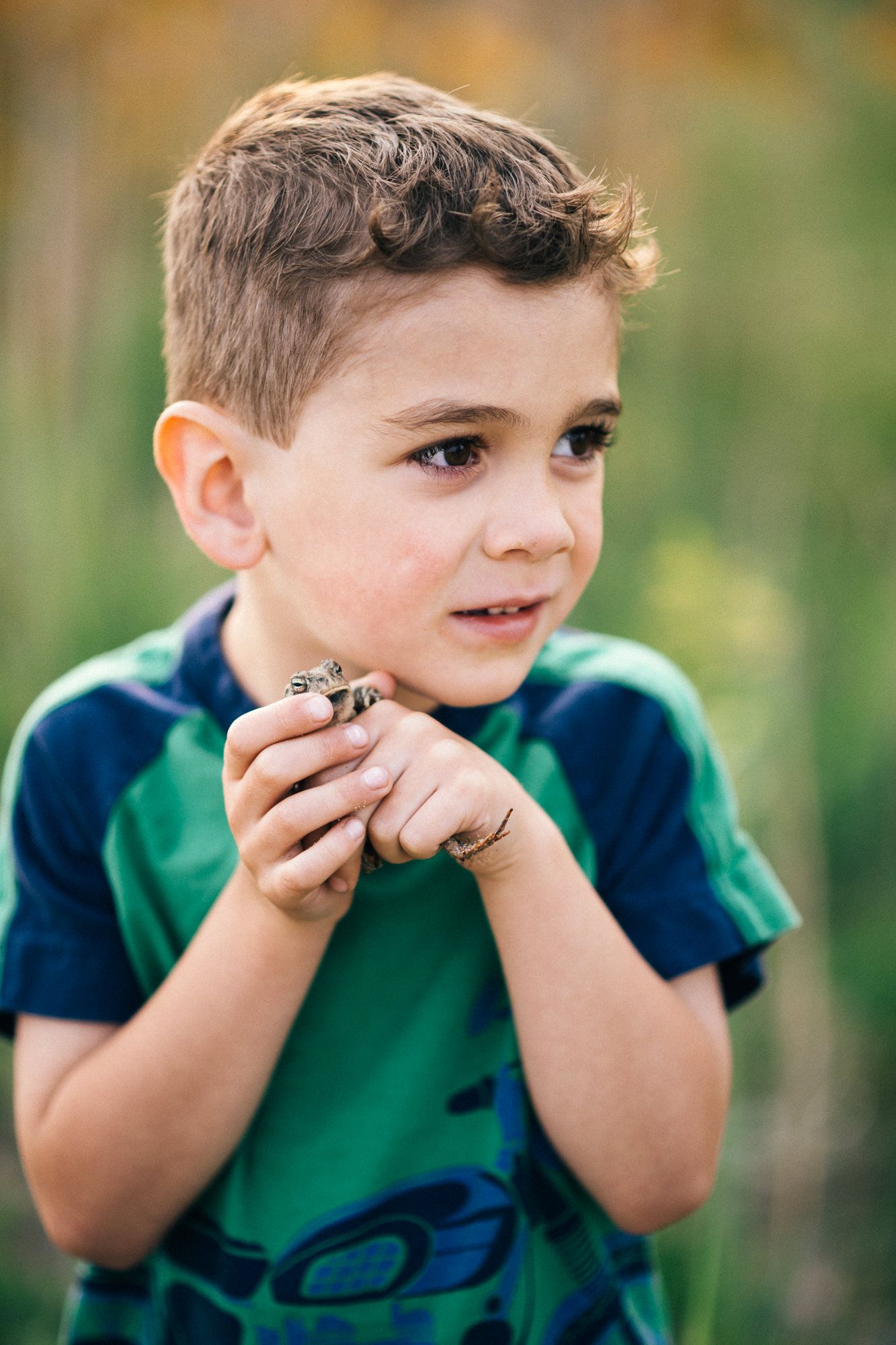 Child in green shirt making silly faces in a series of outdoor portraits.