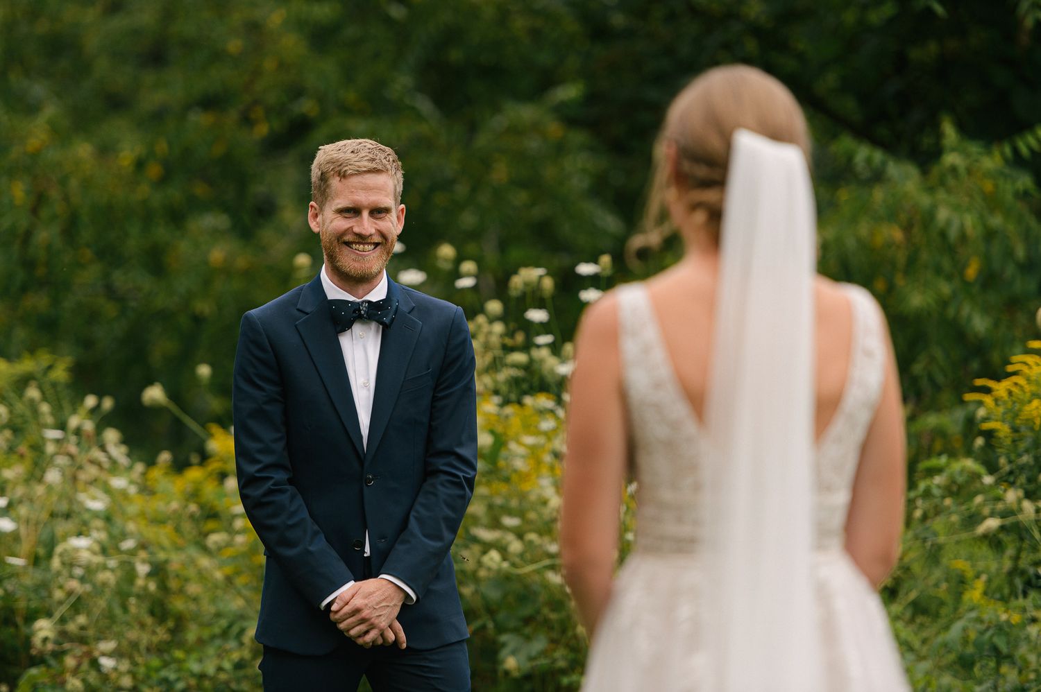 Wedding couple poses in a field of wildflowers on their special day.