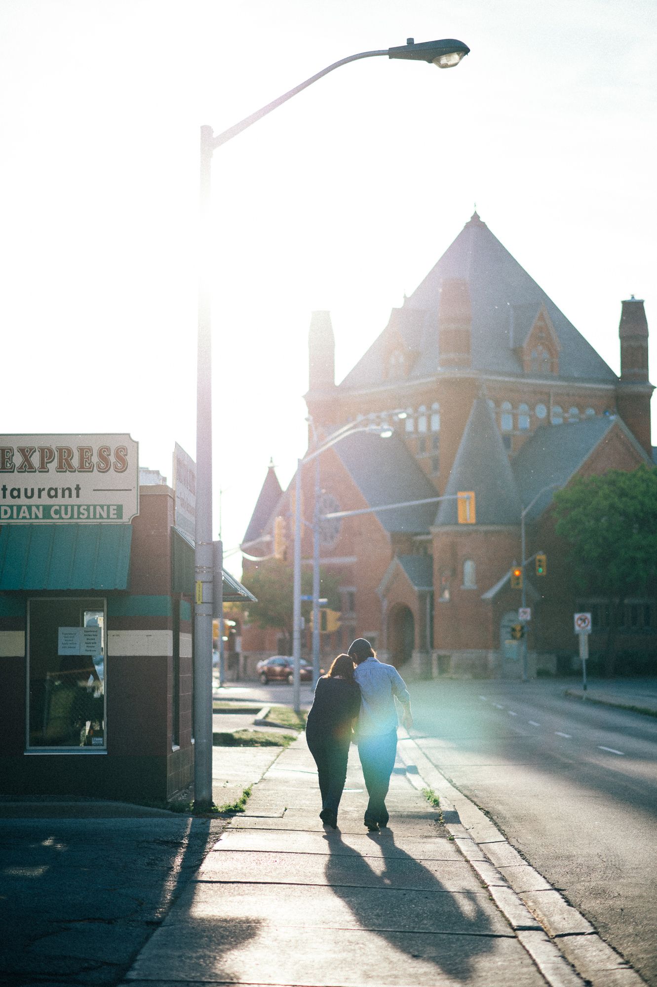 Silhouettes of people walking near historic brick buildings at sunset.