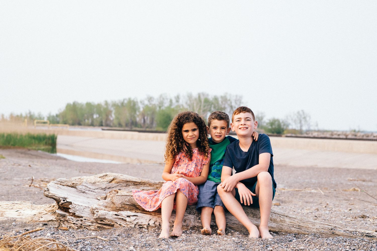 Family sitting together on a rocky beach shoreline.
