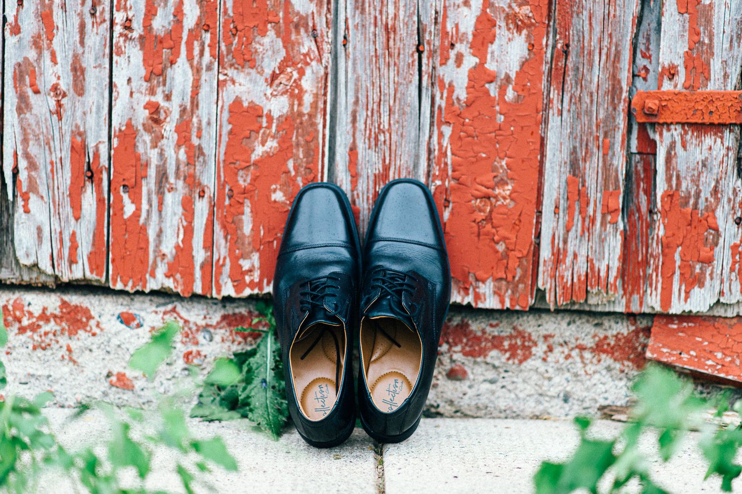 Wedding shoes arranged against weathered red barn wood background.
