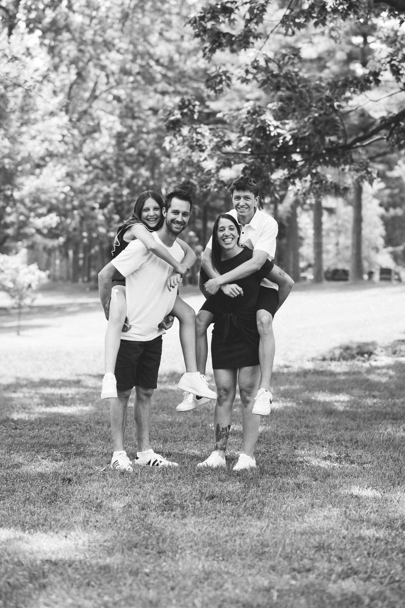 Black and white photo of friends posing playfully on grass in a park.