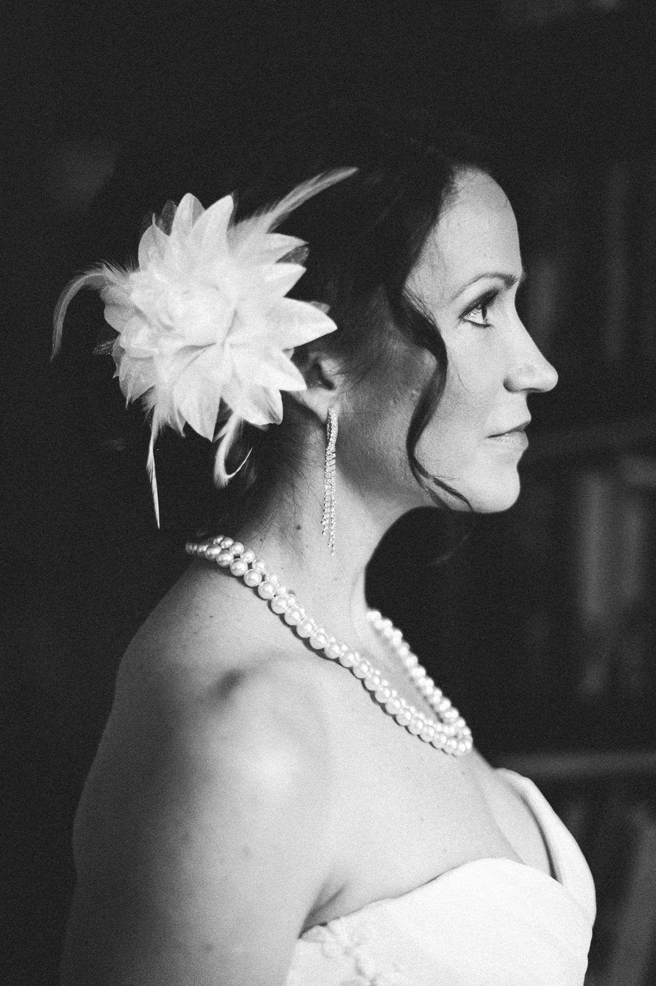 Classic black and white bridal portrait featuring pearl necklace and white floral hair accessory.