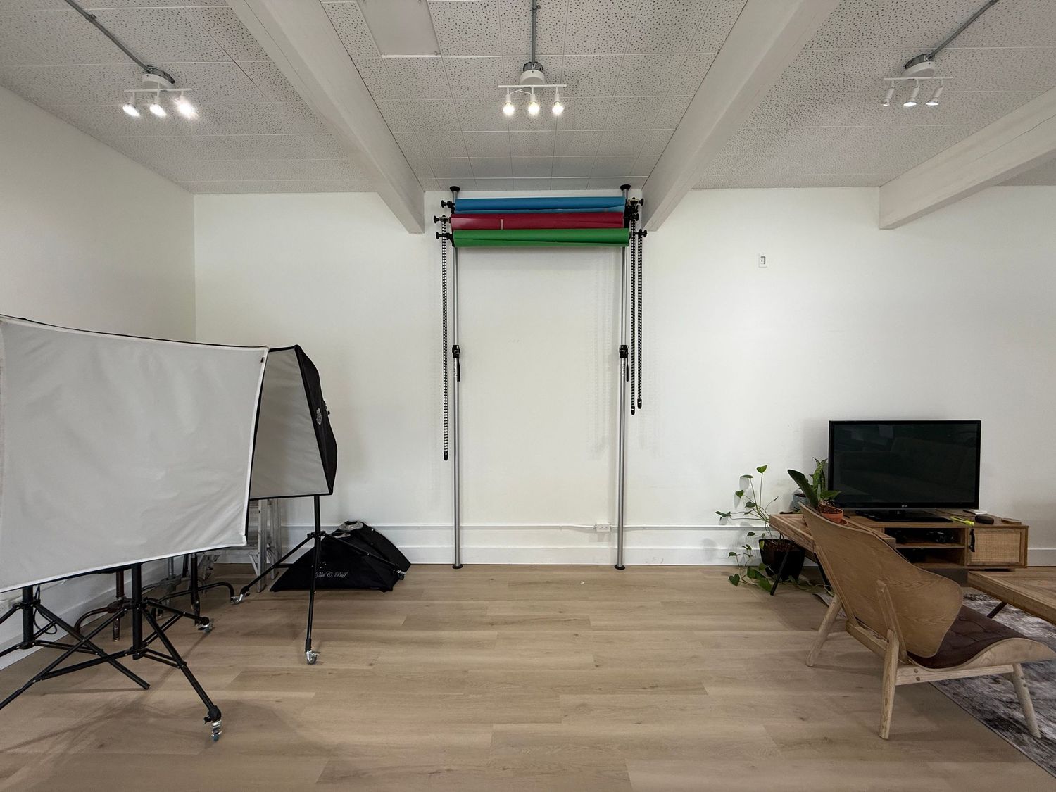 Empty photography studio space with white walls, lighting equipment, and scattered cardboard boxes on the floor.