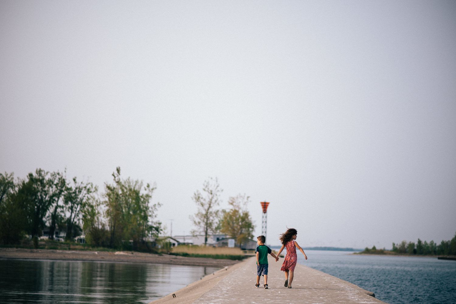 People walking along a misty waterfront path on an overcast day.