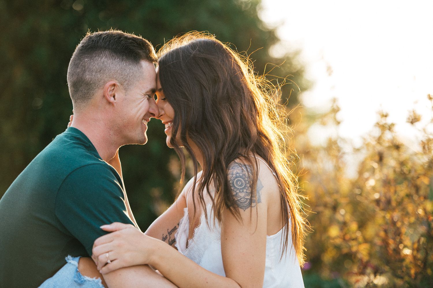 A couple shares a romantic moment in warm golden sunset lighting.