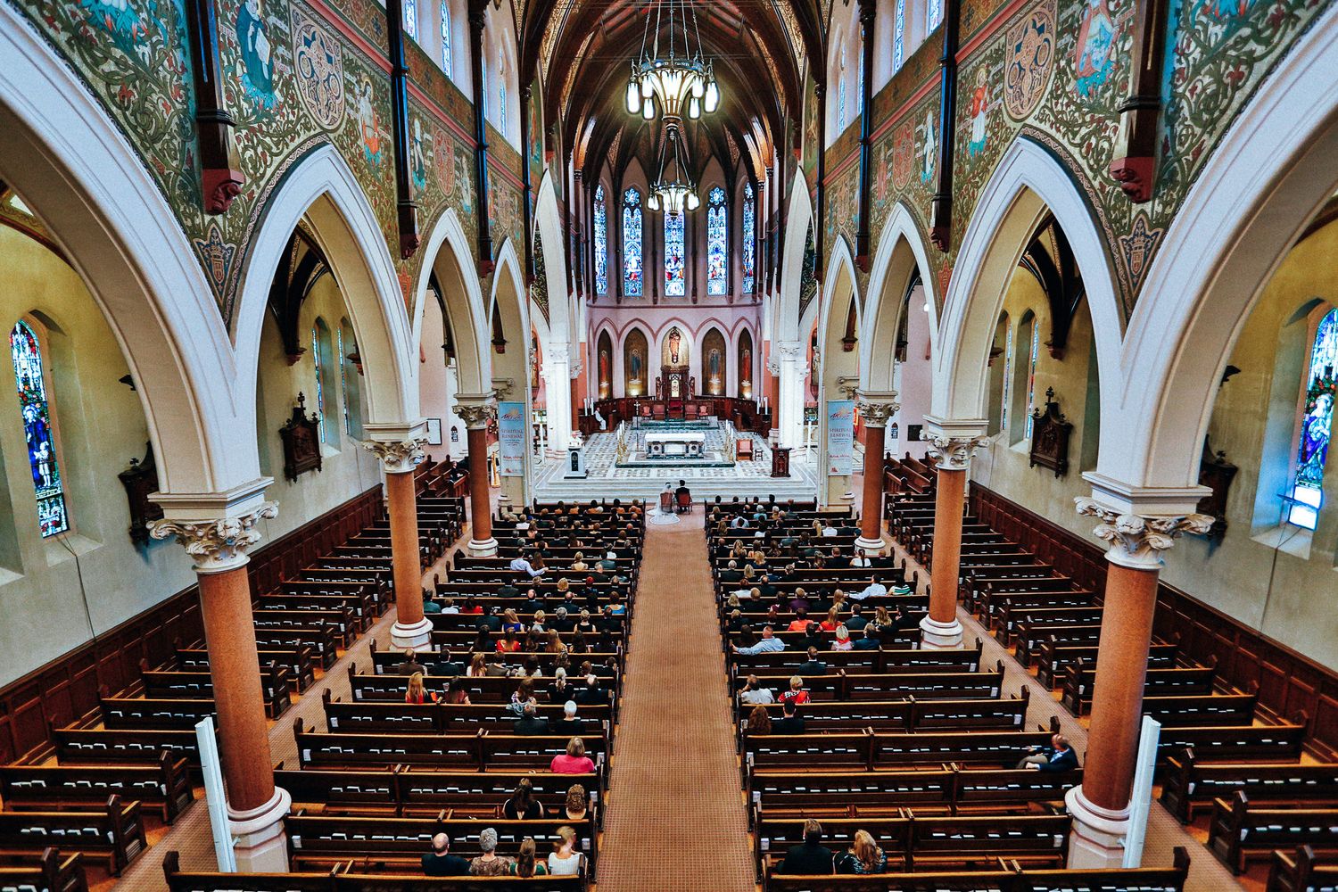 Interior of a grand church with ornate arches and pews lined up for a wedding ceremony.