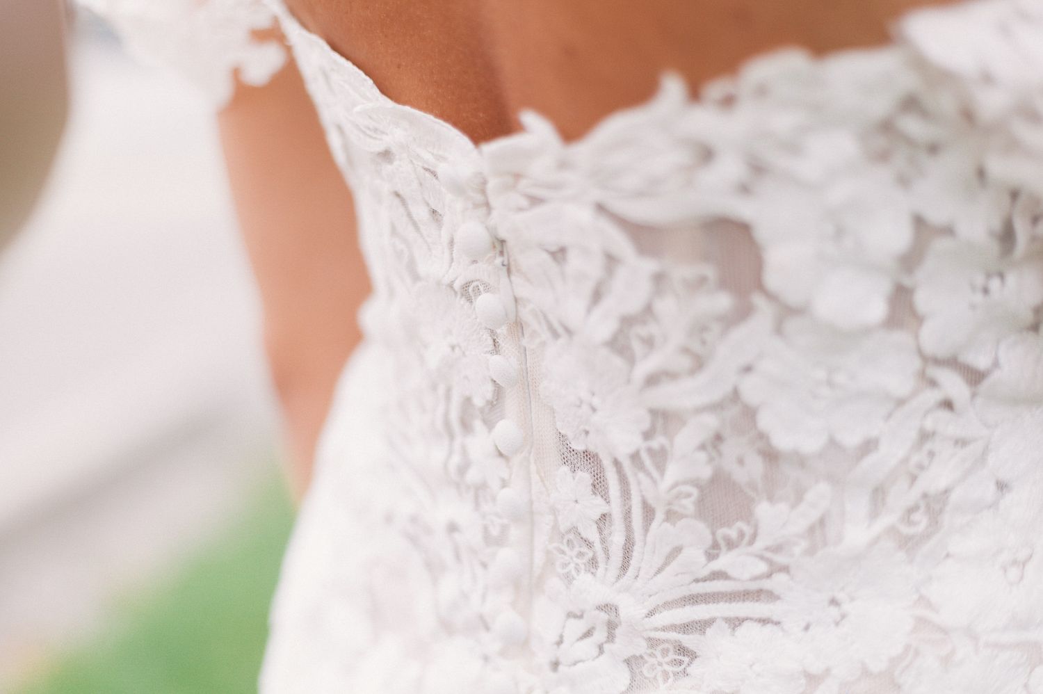 Close-up detail of delicate white lace and beading on a wedding dress bodice.