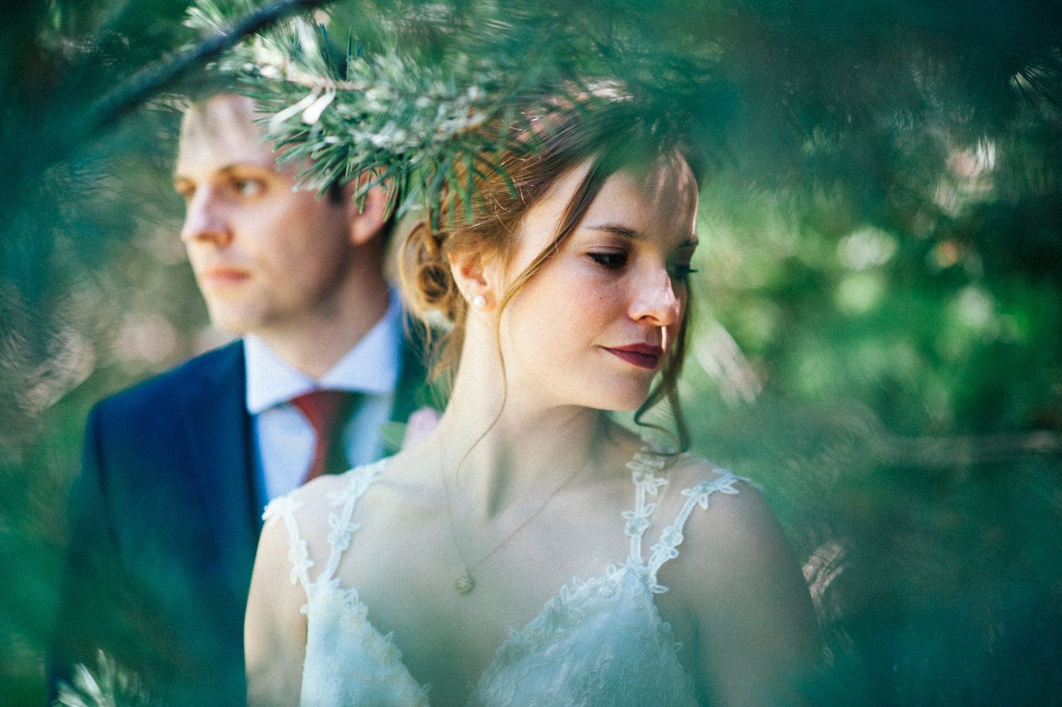 Romantic couple shares intimate moments in a lush green outdoor setting during a wedding photo session.