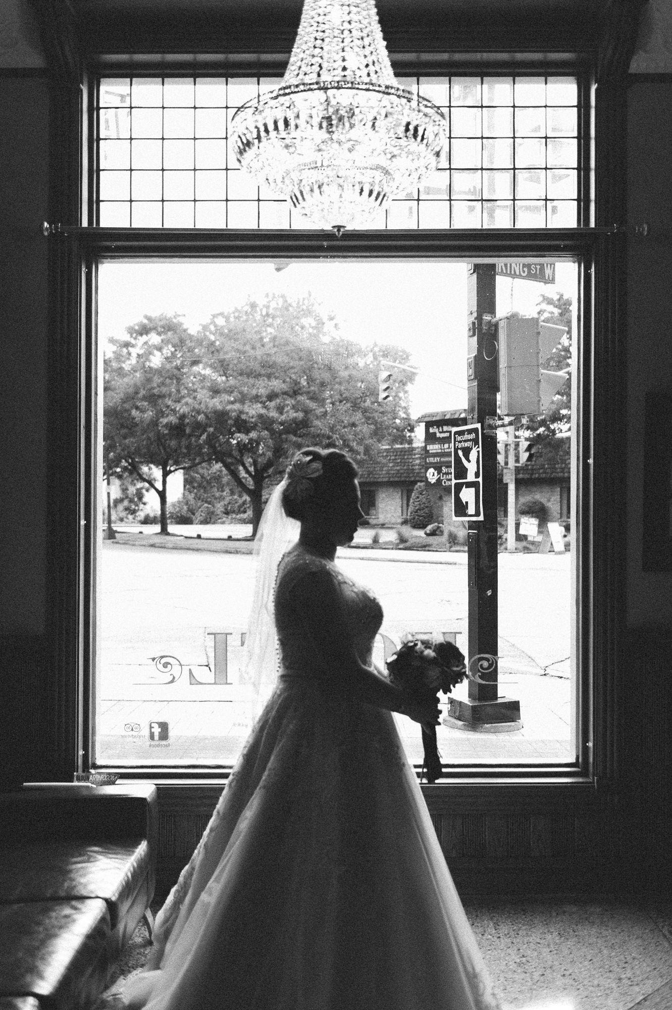 Silhouettes against bright windows in an elegant venue with crystal chandeliers.