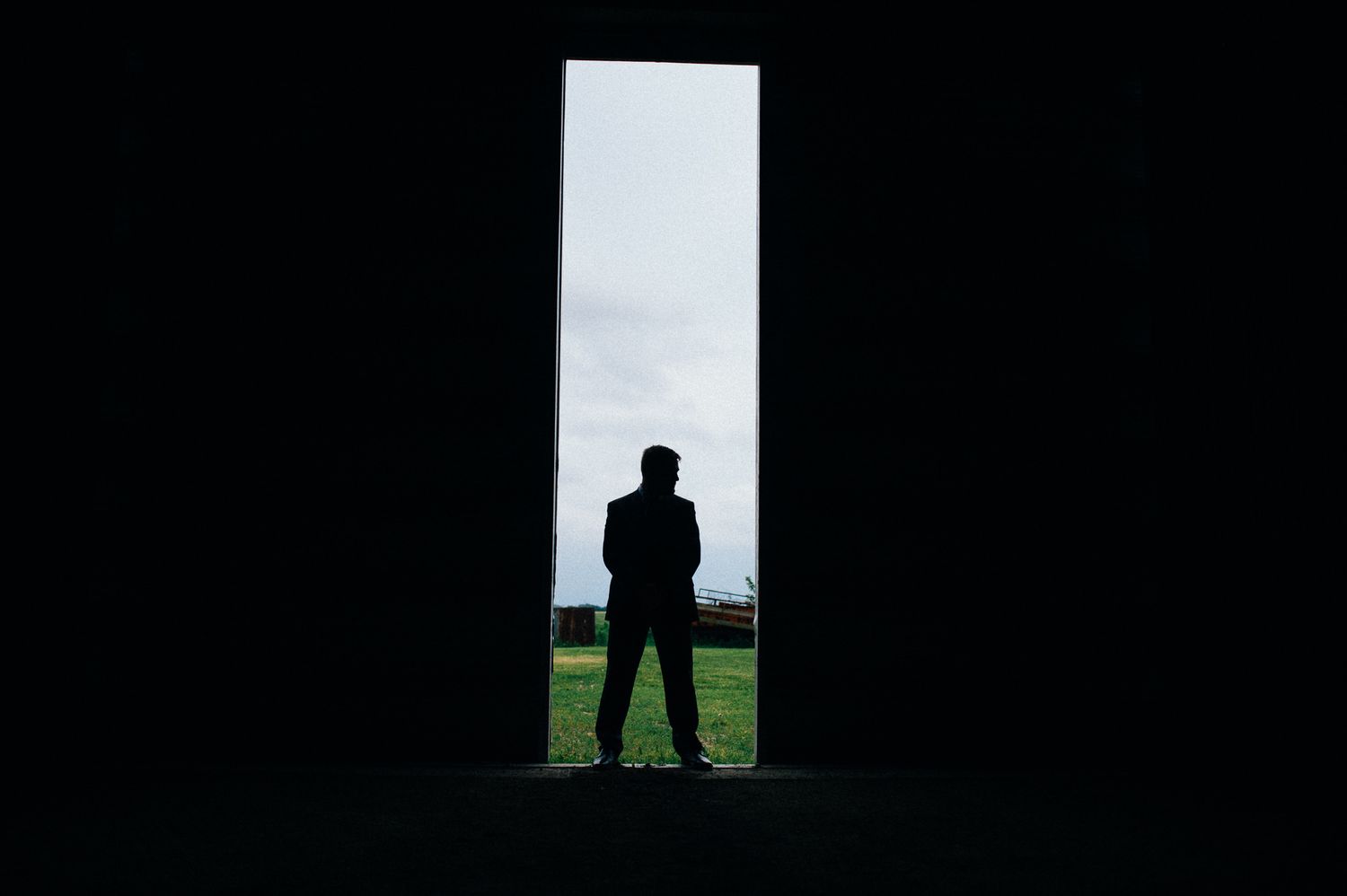 Dramatic silhouette of person standing in doorway against bright background.