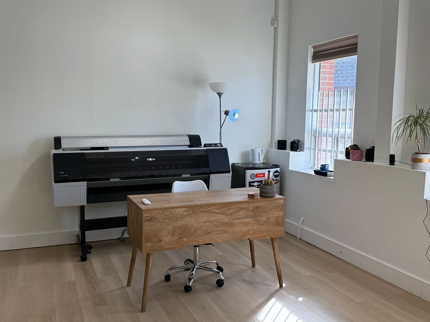 Modern minimalist living room with light wood flooring, white walls, and a sleek black piano near the window.