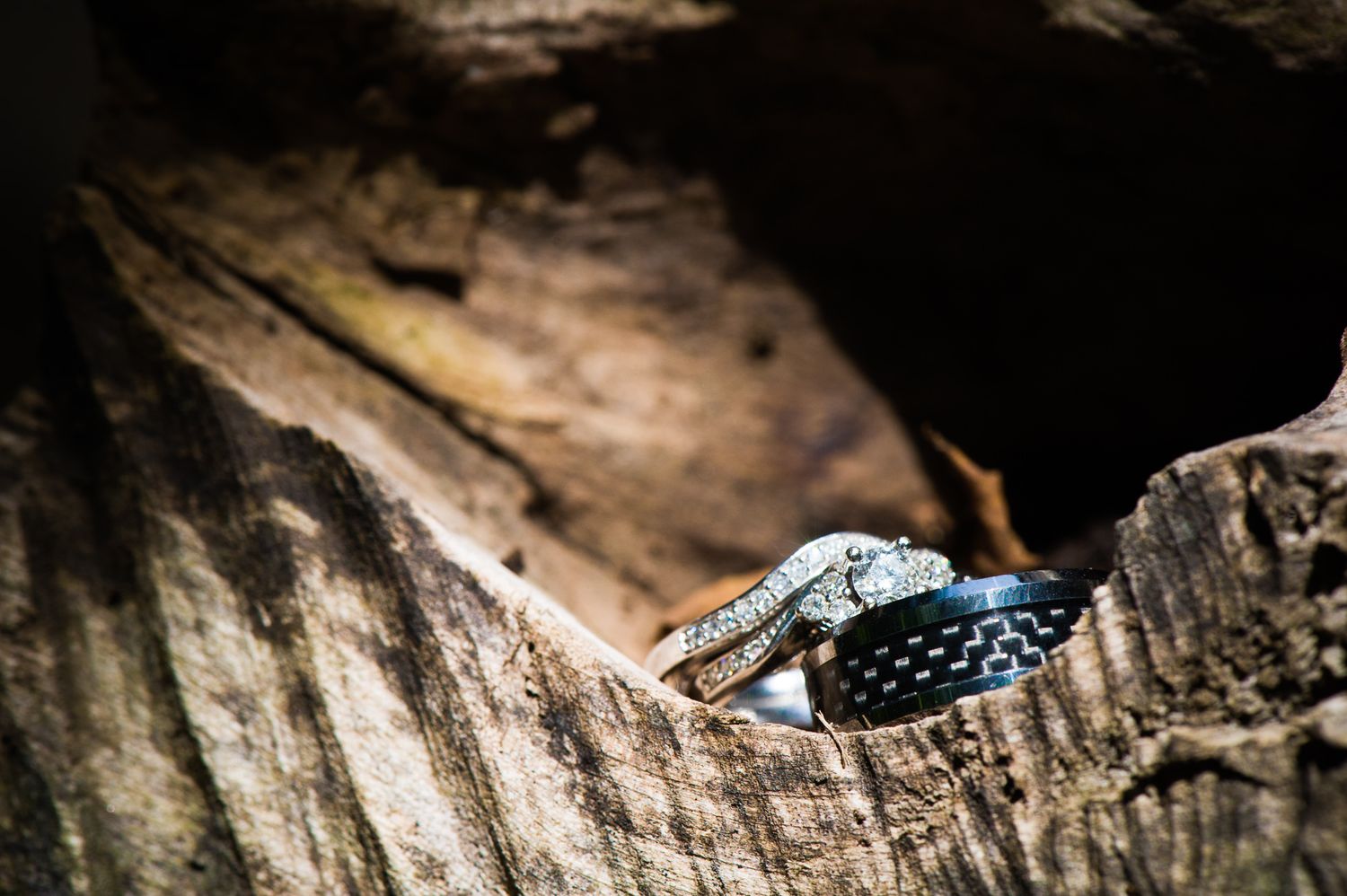Close-up detail shot of wedding rings on rustic wooden texture.
