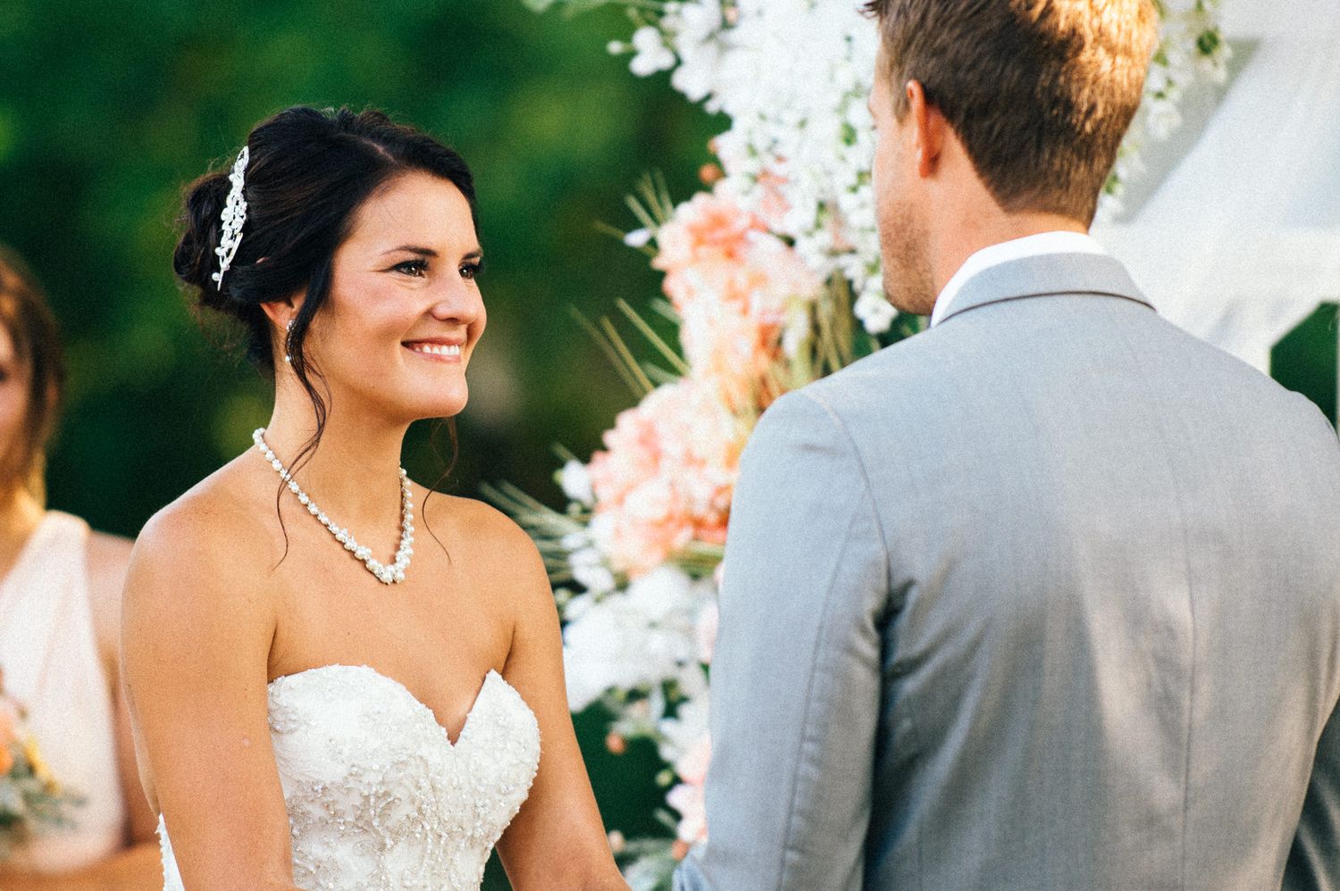 Wedding ceremony scene with couple exchanging vows under floral decorations outdoors.