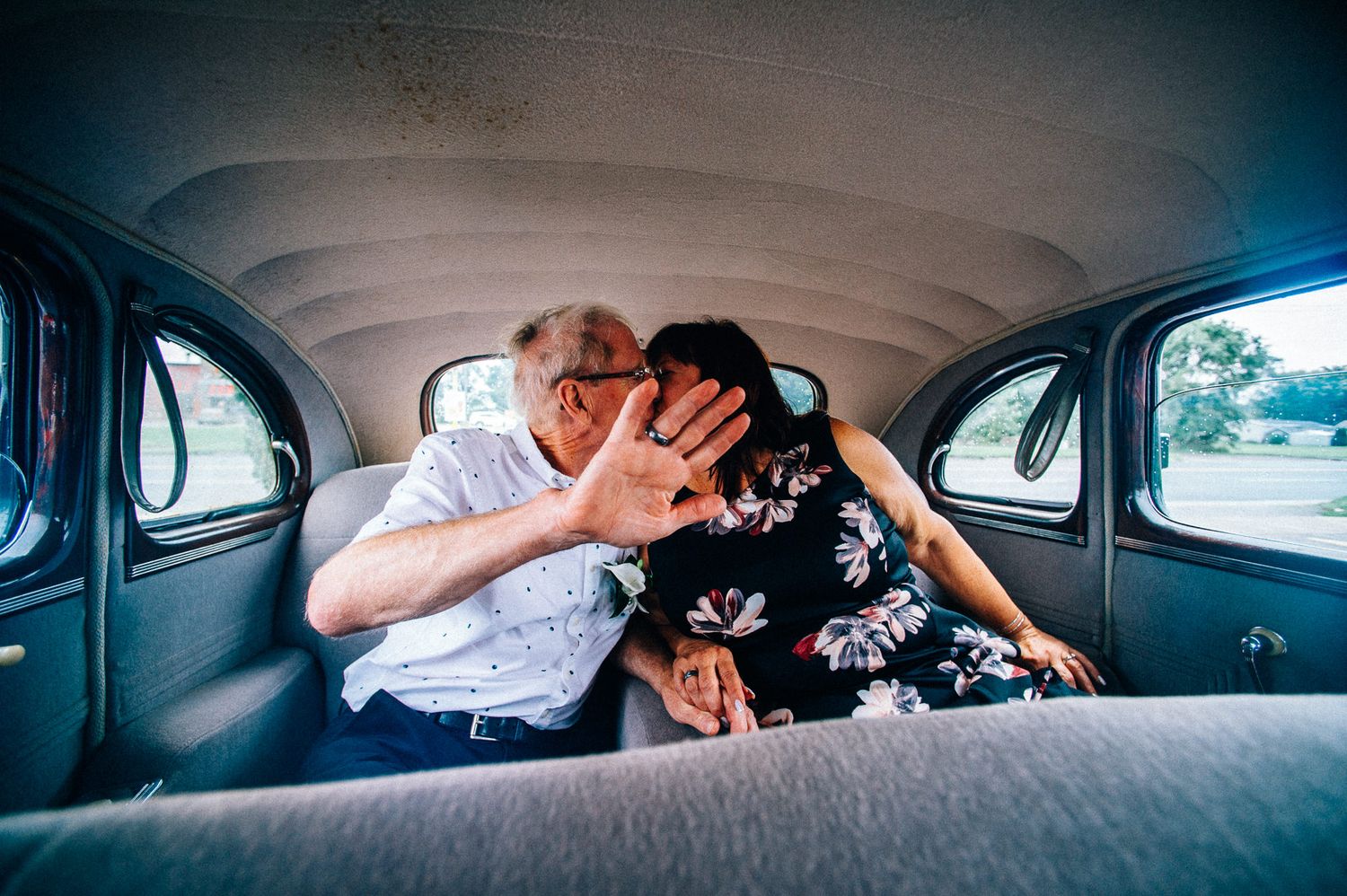 Playful couple sharing intimate moment in back seat of classic car.
