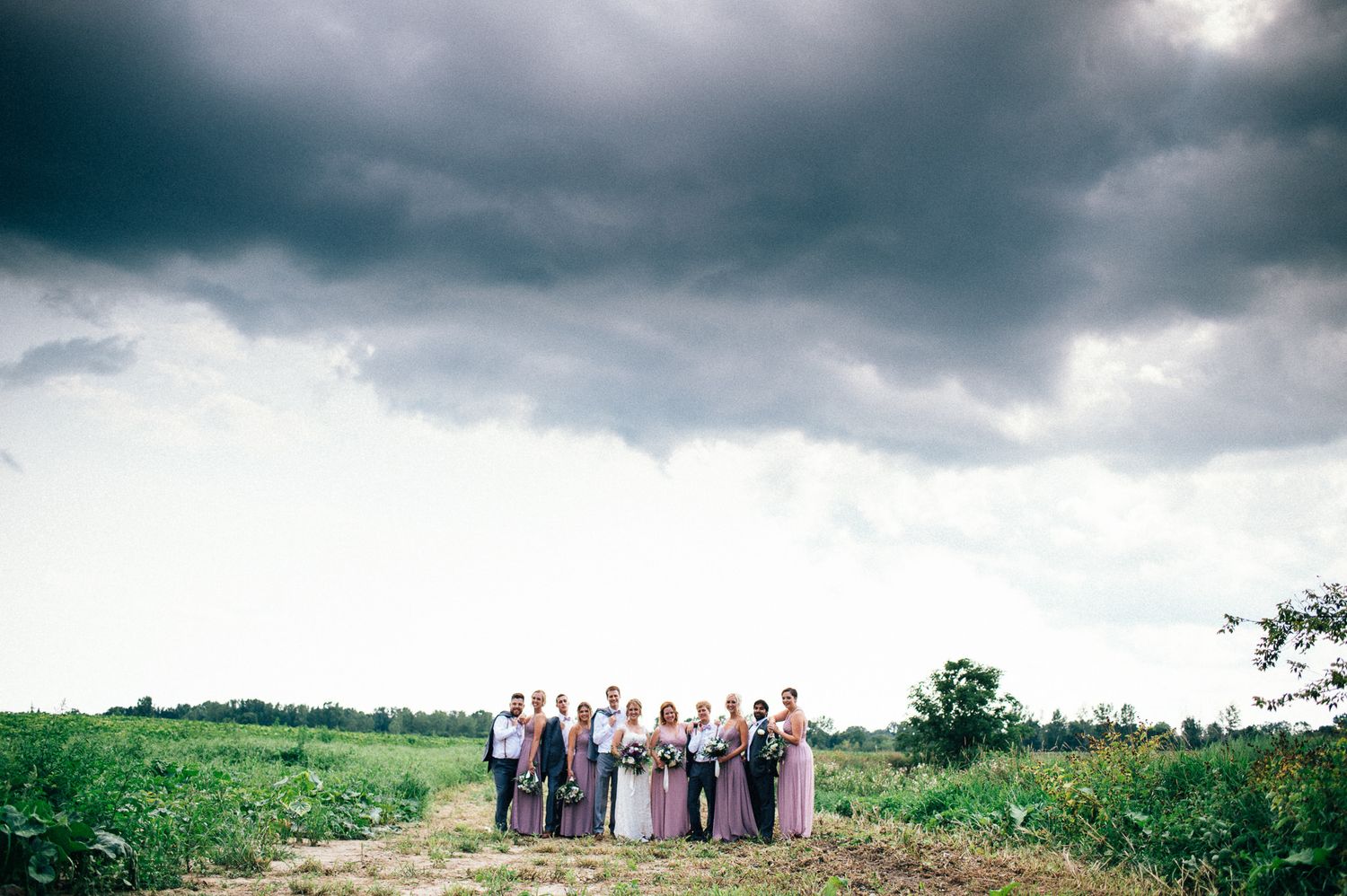 Dramatic stormy sky over a wedding party group photo on a hilltop.