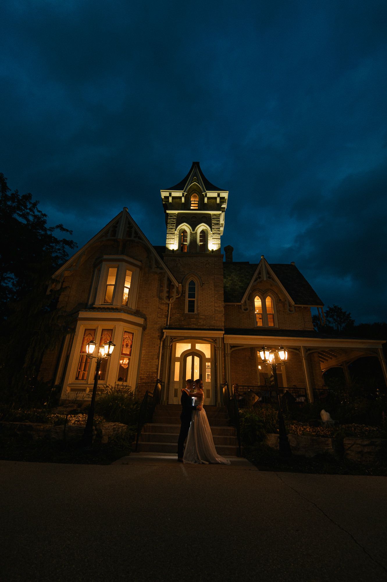 Historic mansion illuminated at night creates a romantic backdrop for wedding photos.