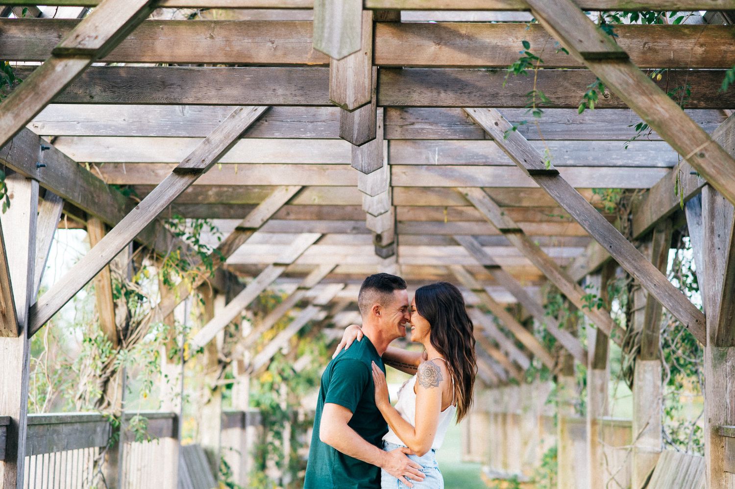 Couple sharing romantic moments under a rustic wooden pergola.