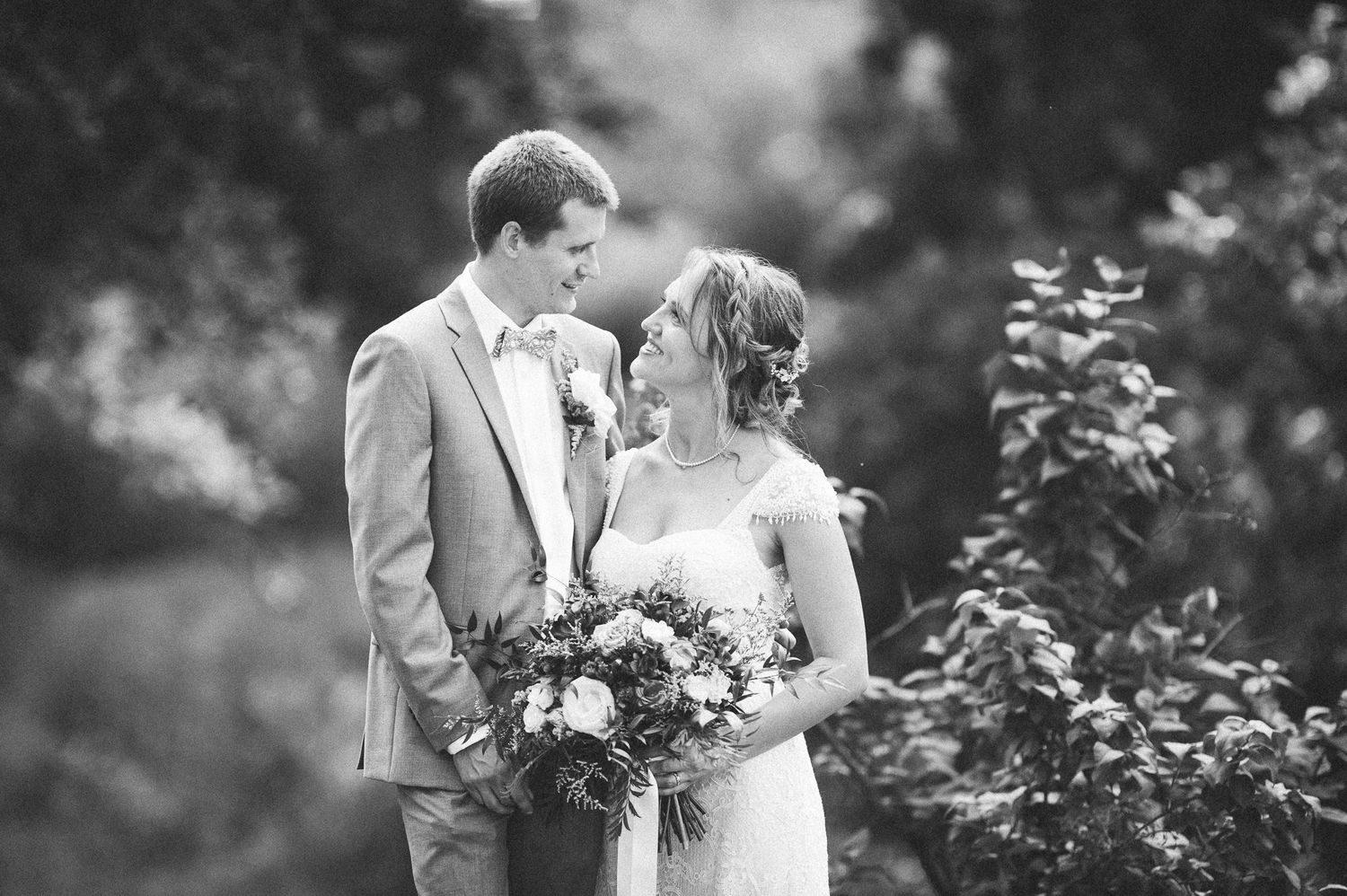 Black and white wedding portraits captured in a dreamy outdoor garden setting.