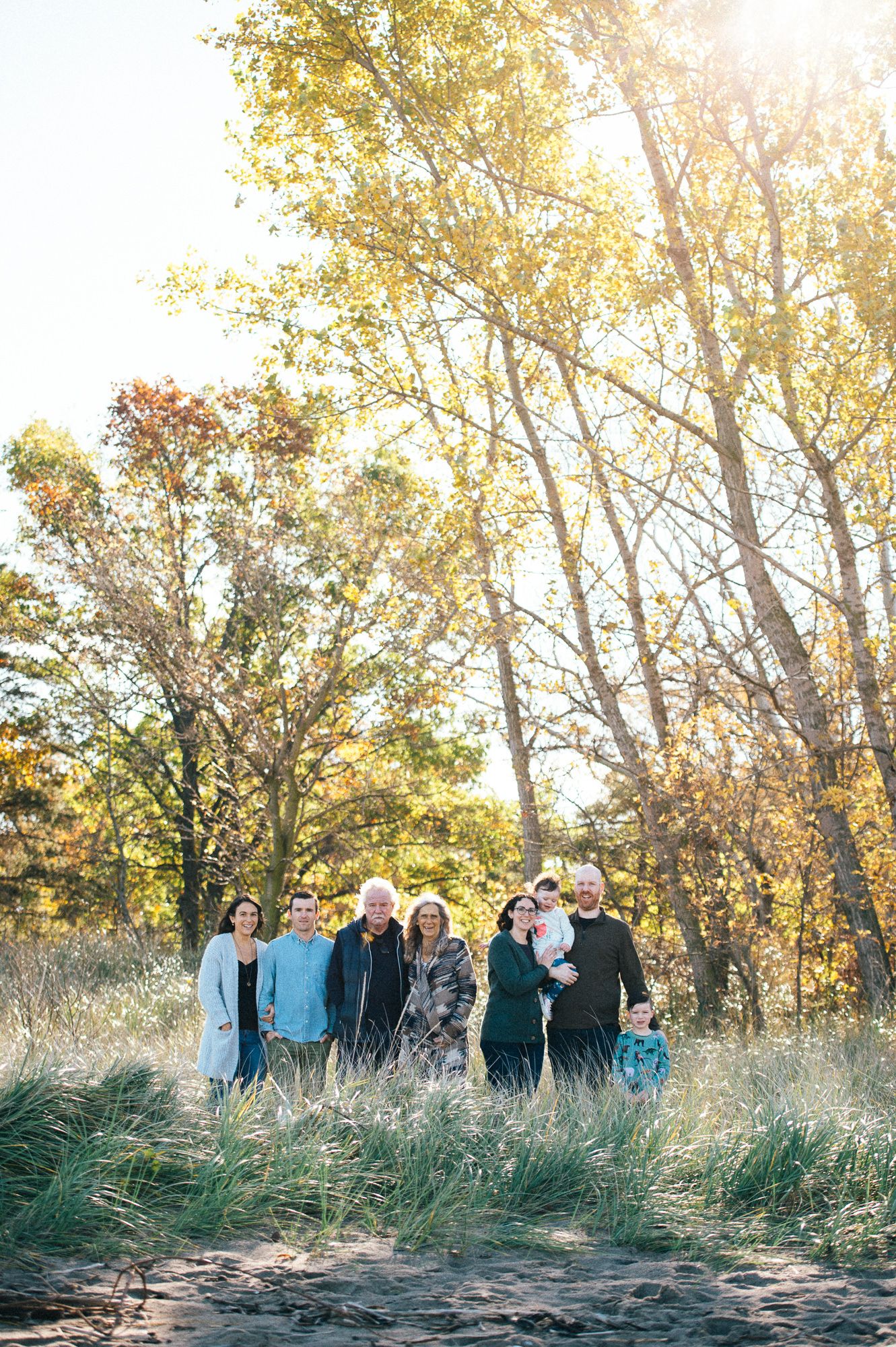 Group photo of people standing in tall grass during golden hour sunset.