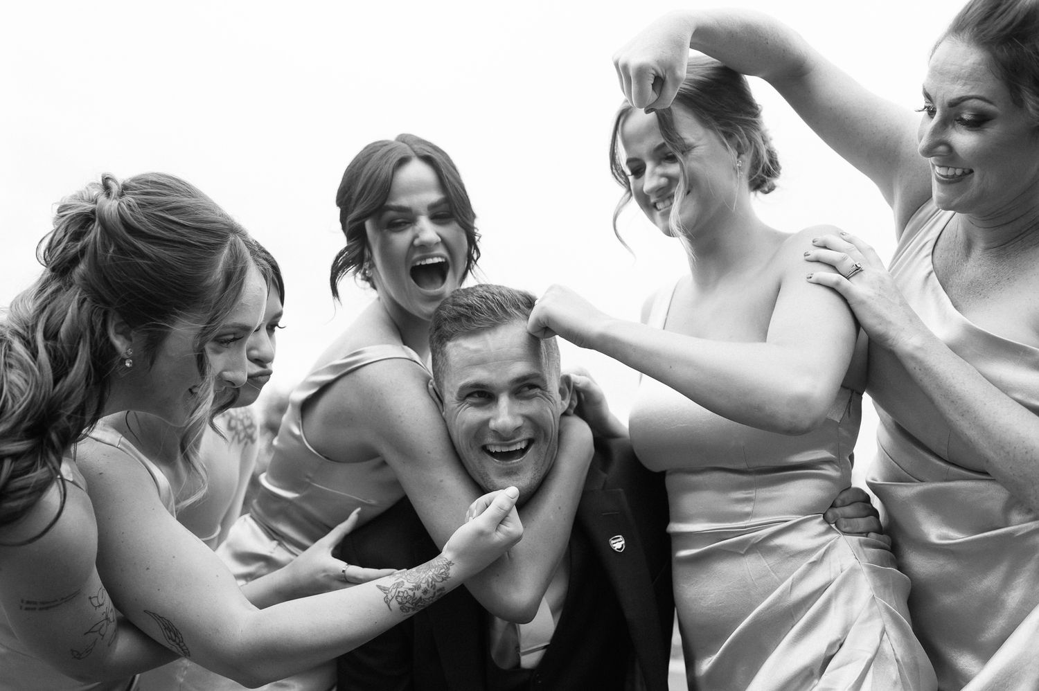 Candid black and white photo of wedding party laughing together.