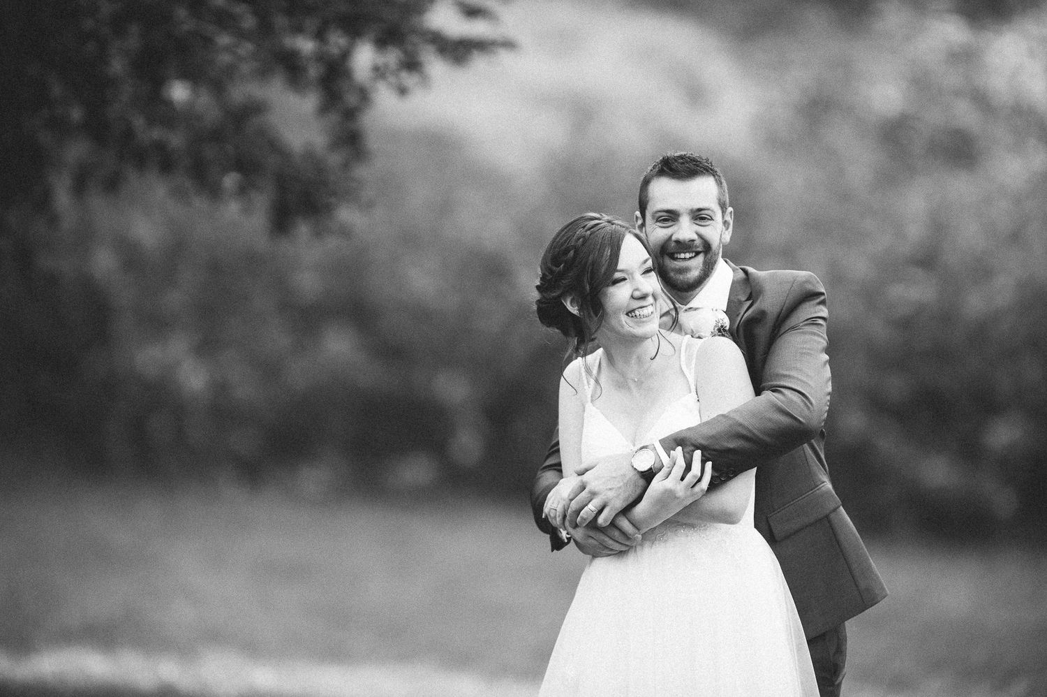 Black and white portrait of newlyweds embracing outdoors.