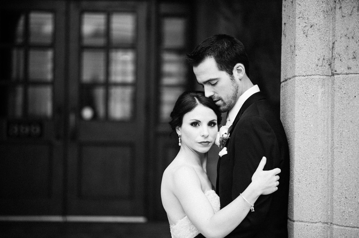 Dramatic black and white portrait against stone architecture.