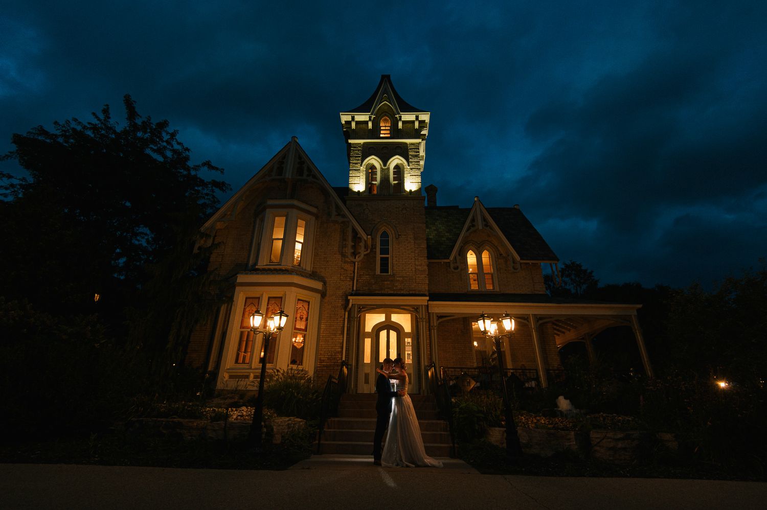 Historic Victorian mansion lit up at night with ornate architectural details.