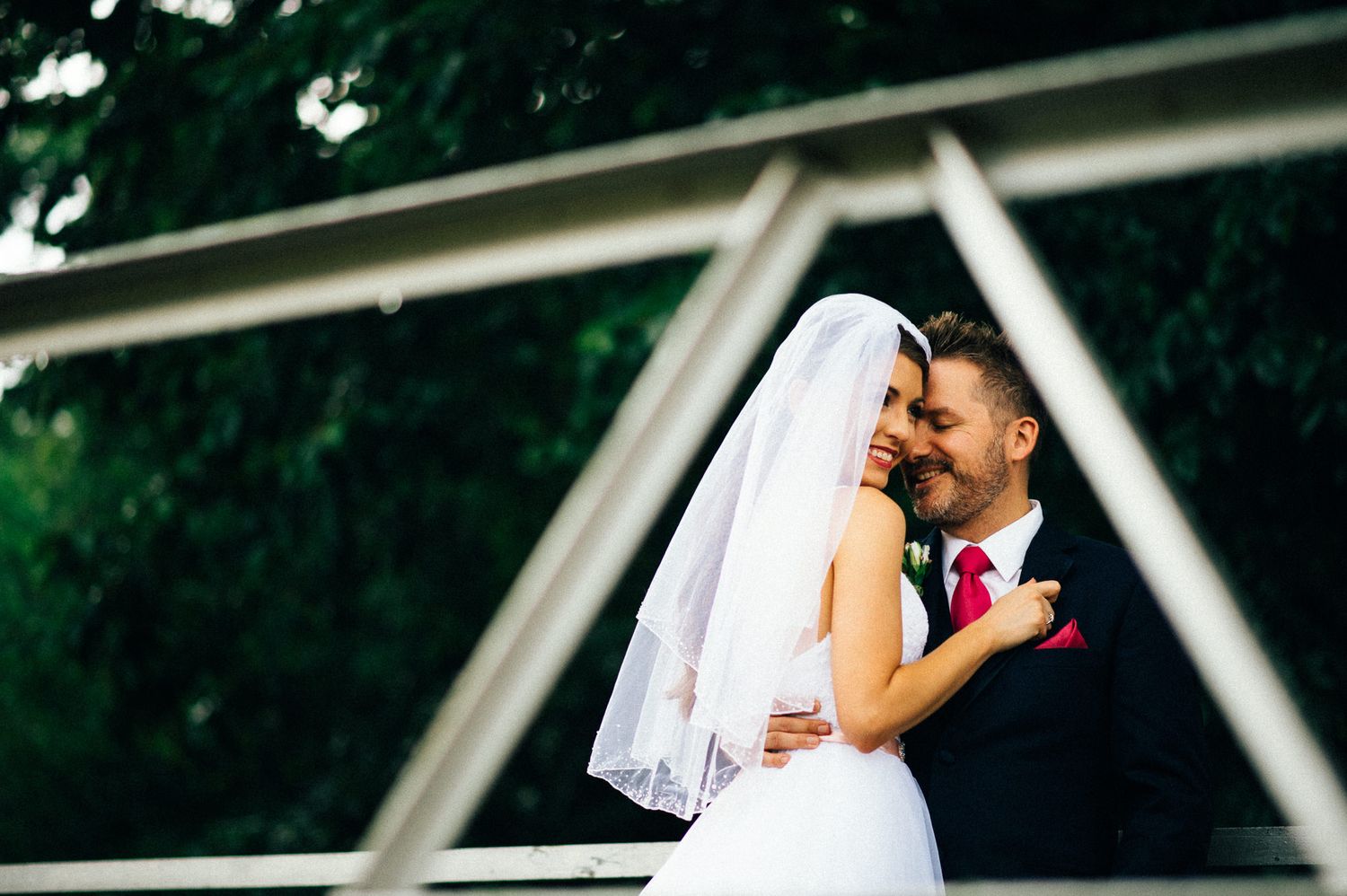 Newlyweds sharing romantic moment under geometric architectural structure.