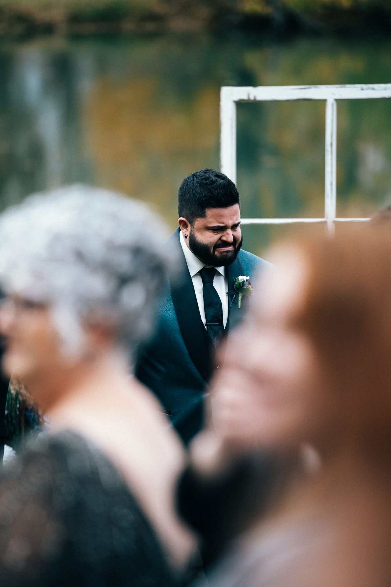 Wedding guests seated at ceremony with selective focus on attendee in dark suit.