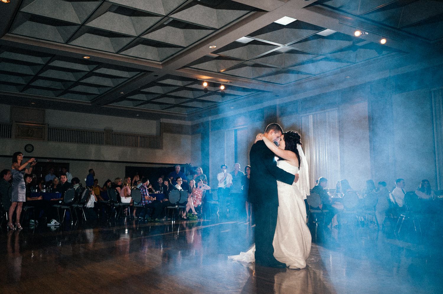 First dance in a blue-lit reception venue with dramatic smoke effects.