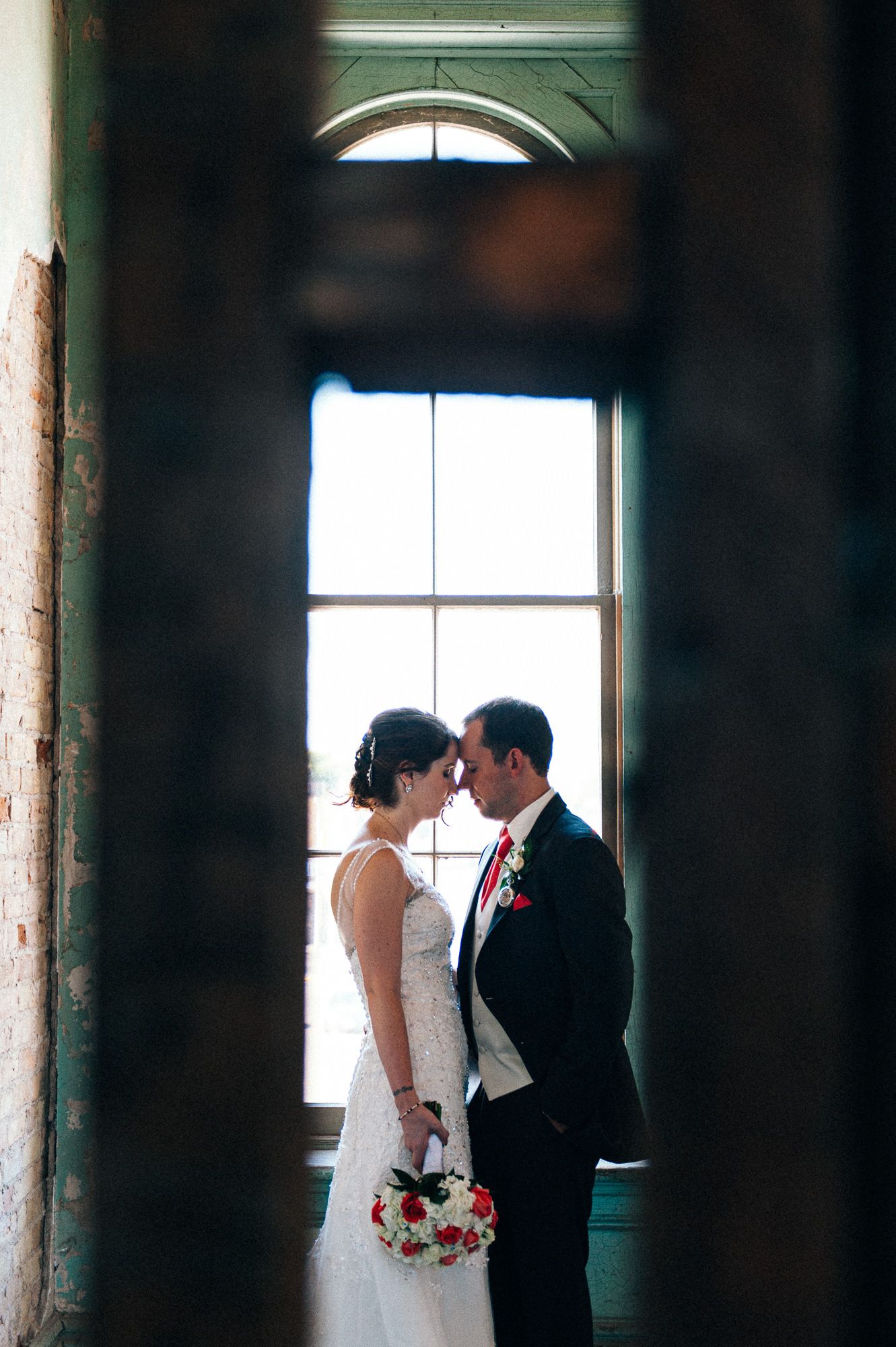 Romantic silhouette of couple by window in intimate wedding moment.
