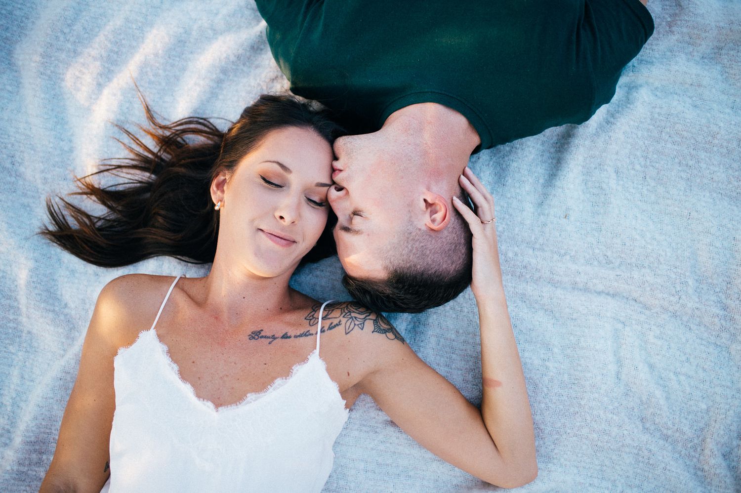A couple lies close together on a blanket during an intimate photoshoot.