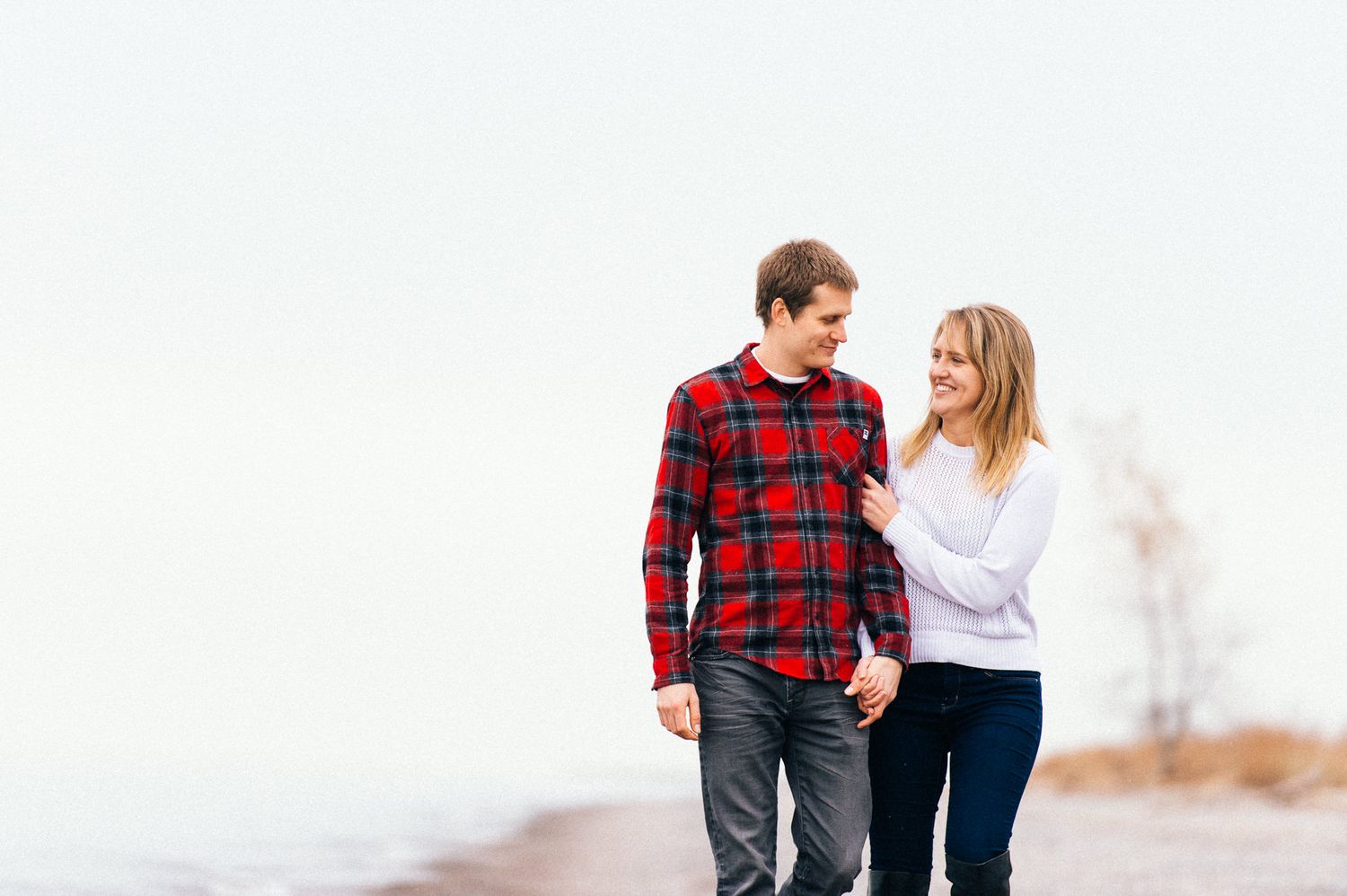 A couple stands close together outdoors wearing coordinated casual outfits.