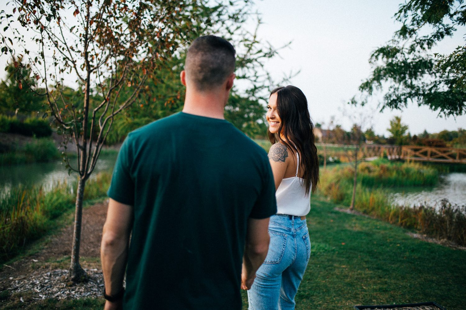 Couple walking together near a peaceful lake surrounded by trees.