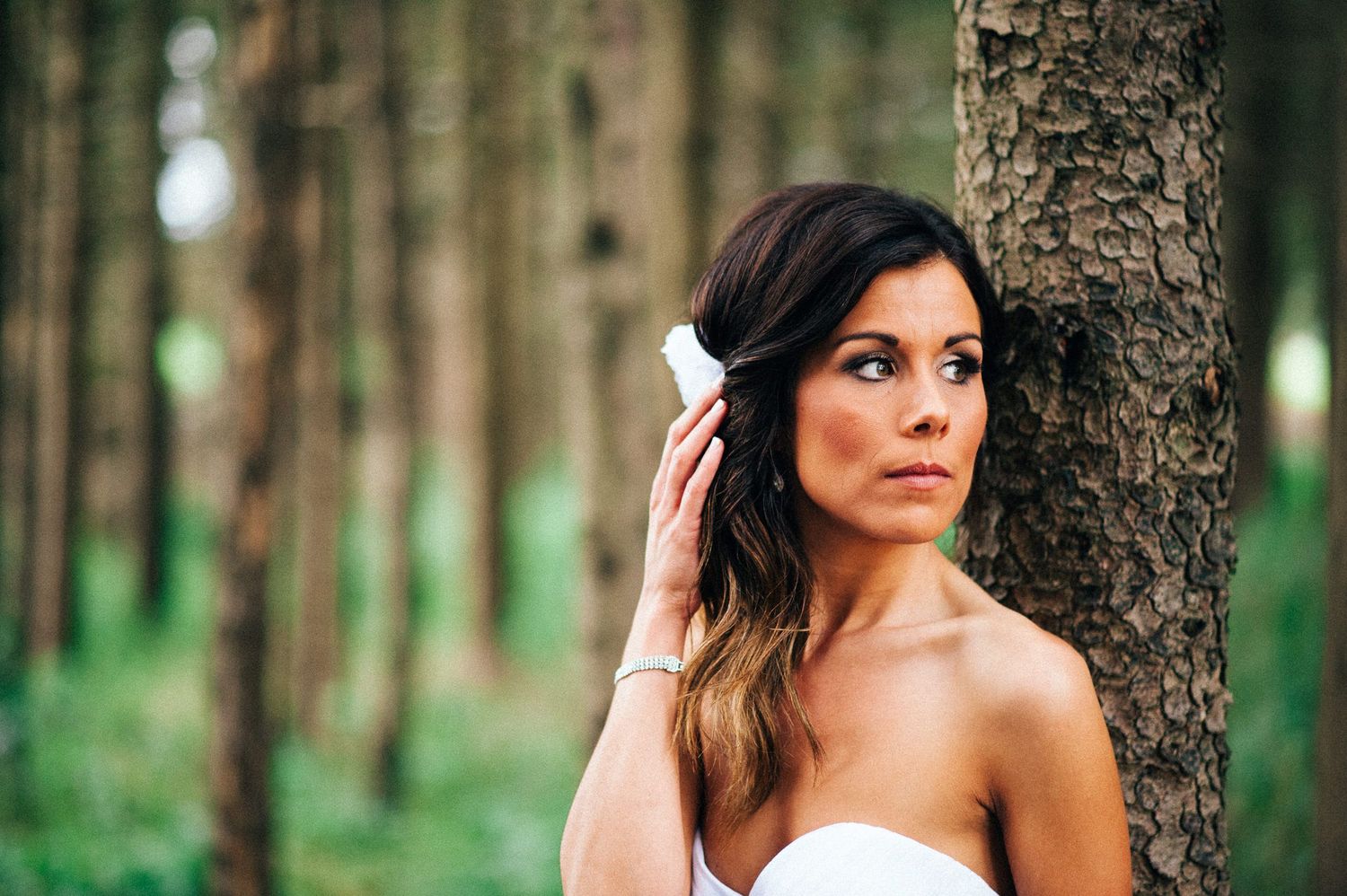 Artistic portraits captured against tree trunks in a serene forest setting.