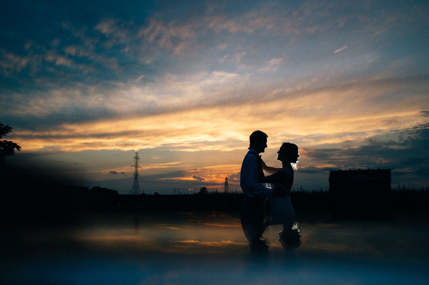 Dramatic sunset silhouettes of a wedding celebration against a colorful sky.